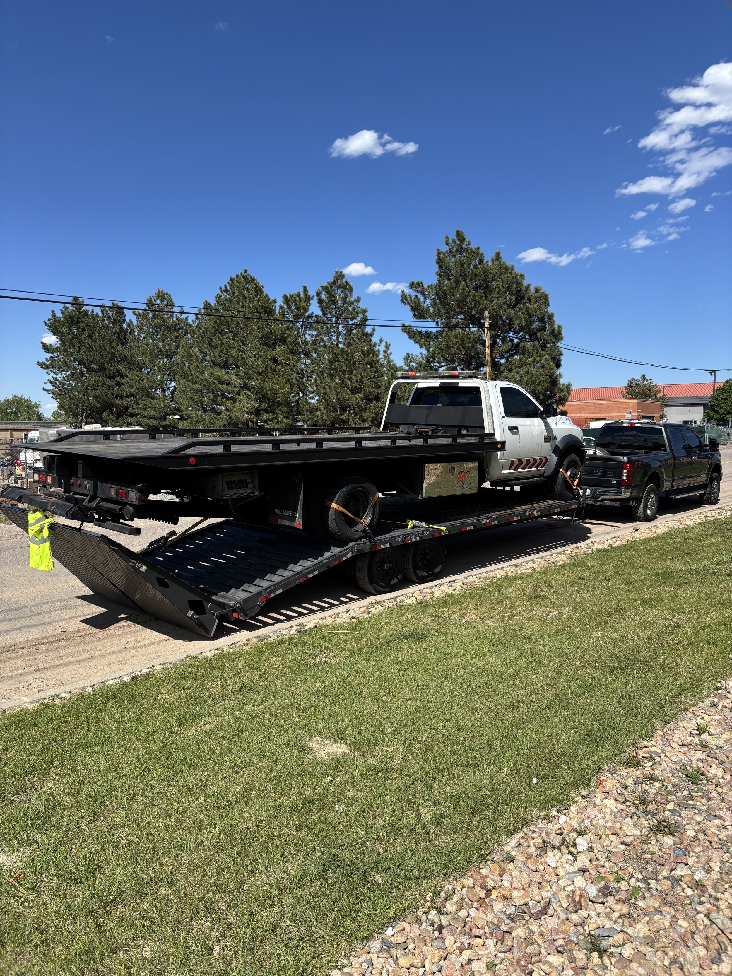 A white flatbed tow truck being towed by one of our light duty trucks on a 35 ft trailer remember we tow anything even tow trucks