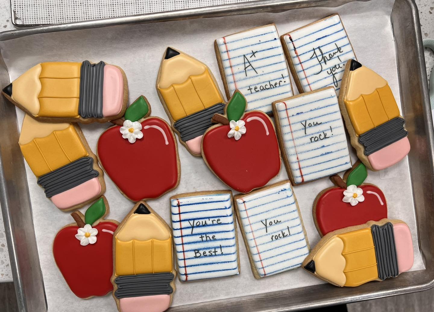 Decorated cookies in school-themed shapes, including red apples, yellow pencils, and lined notepads with teacher appreciation messages.