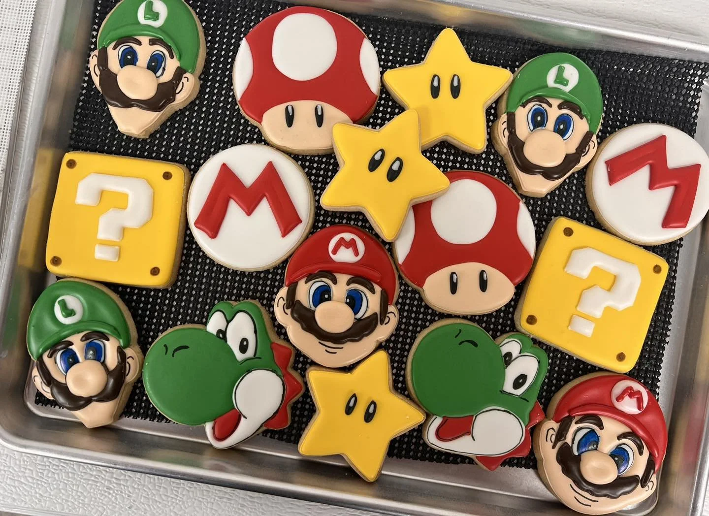 Decorated cookies featuring Super Mario characters and game symbols, including Mario, Luigi, Yoshi, stars, question blocks, mushrooms, and power-up icons.