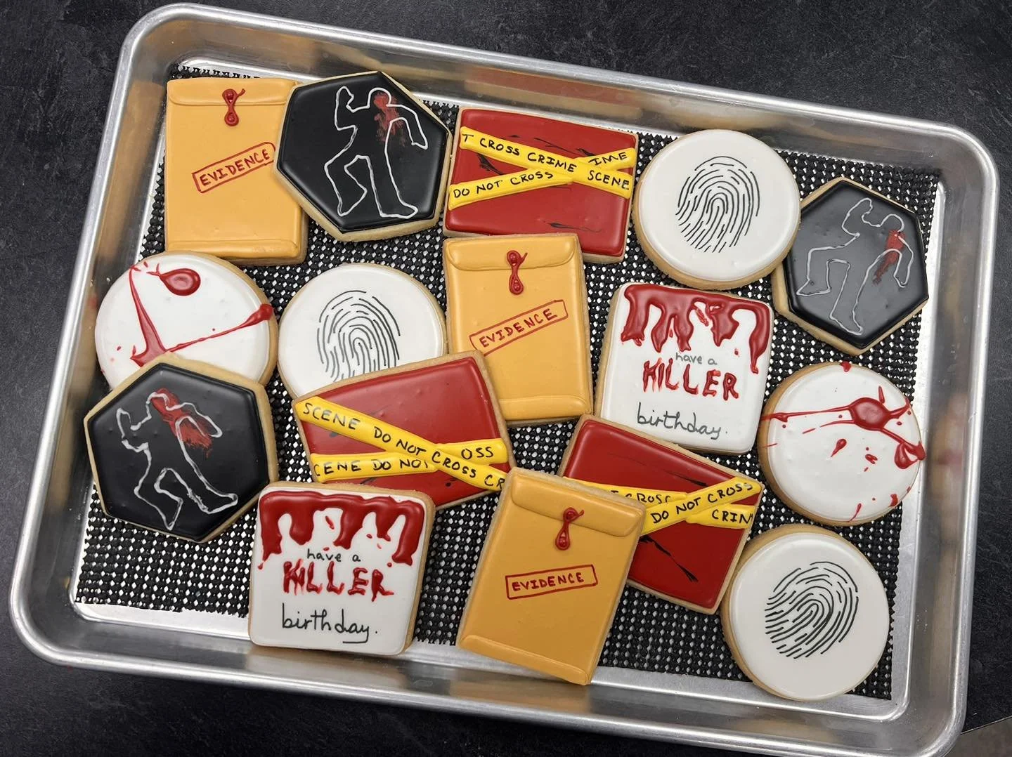 Cookies decorated with crime scene investigation themes, including fingerprint patterns, police tape, footprints, crime evidence labels, and a birthday message for 'Muller' with blood spatter effects.
