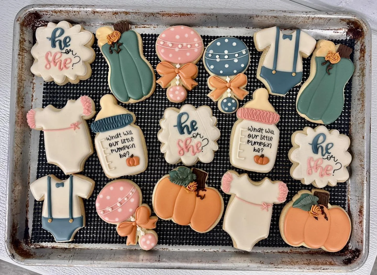 Assorted cookies with fall and gender reveal themes on a baking sheet.
