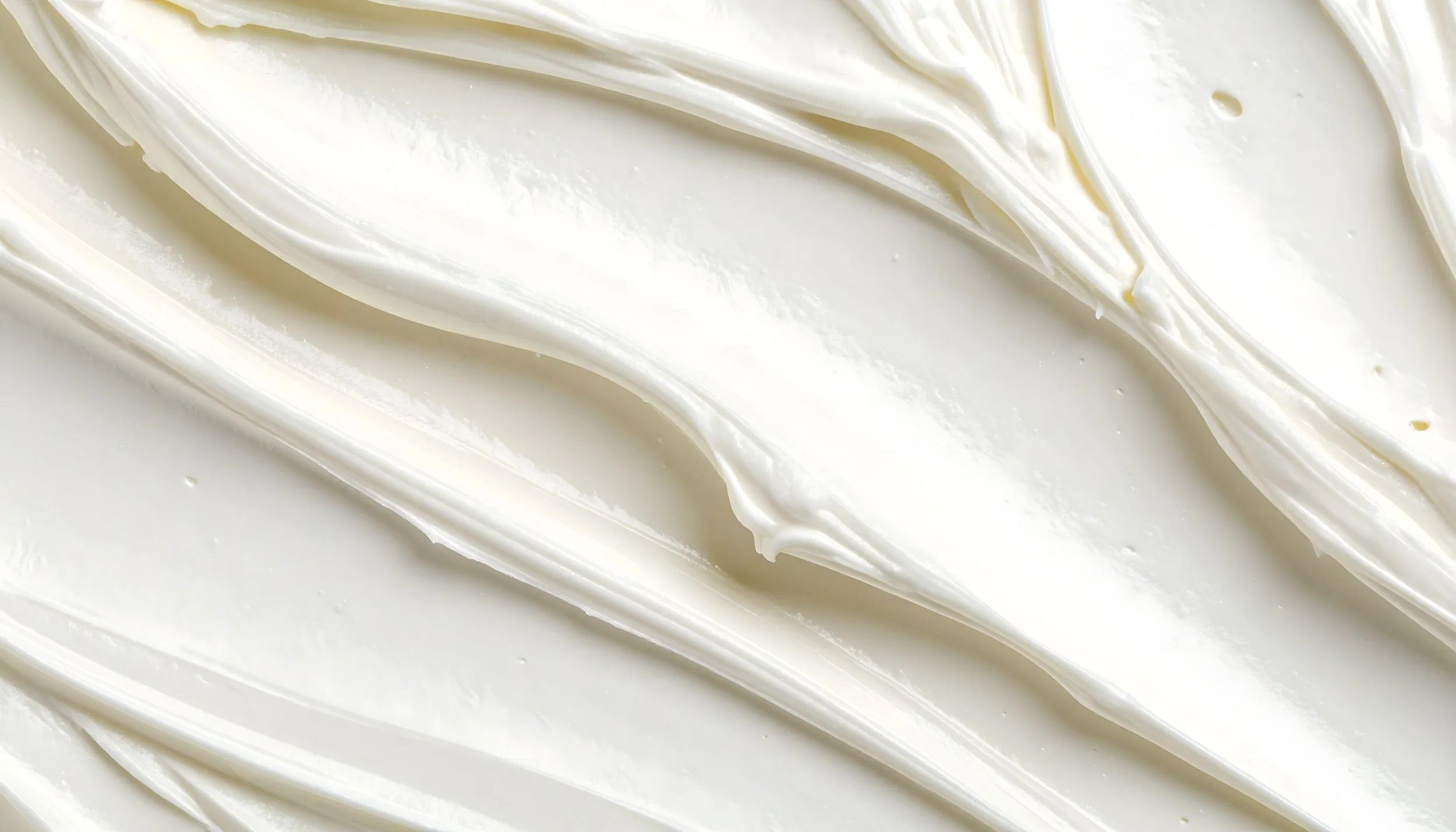 Close-up of smooth, white cream or frosting spread in a wavy pattern.