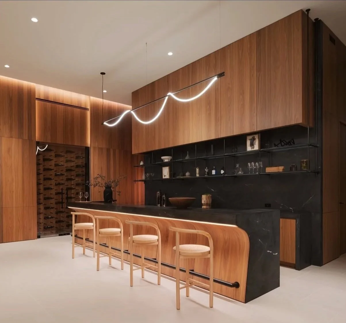 Modern kitchen with black marble island, wooden cabinets, and minimalist light fixture with wave design.