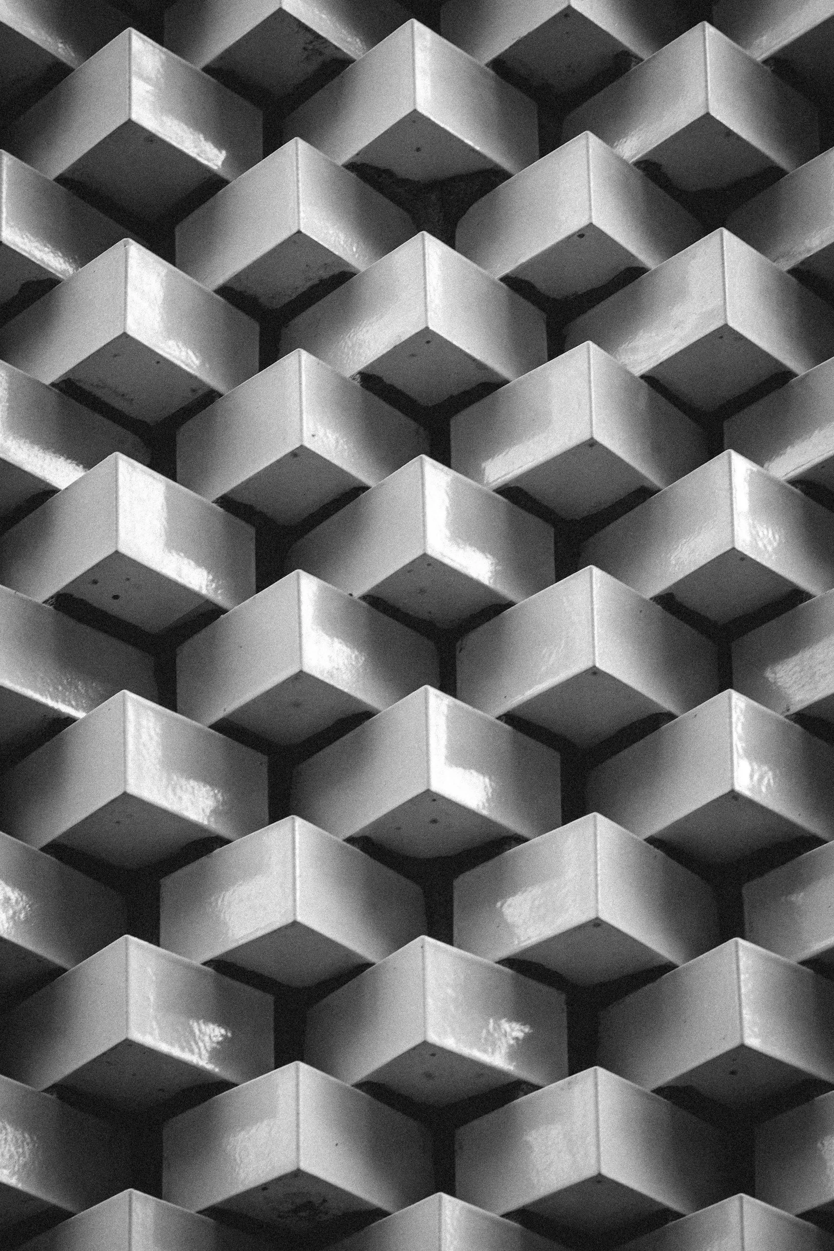 A black and white photo of a geometric pattern formed by stacked, square, three-dimensional objects.