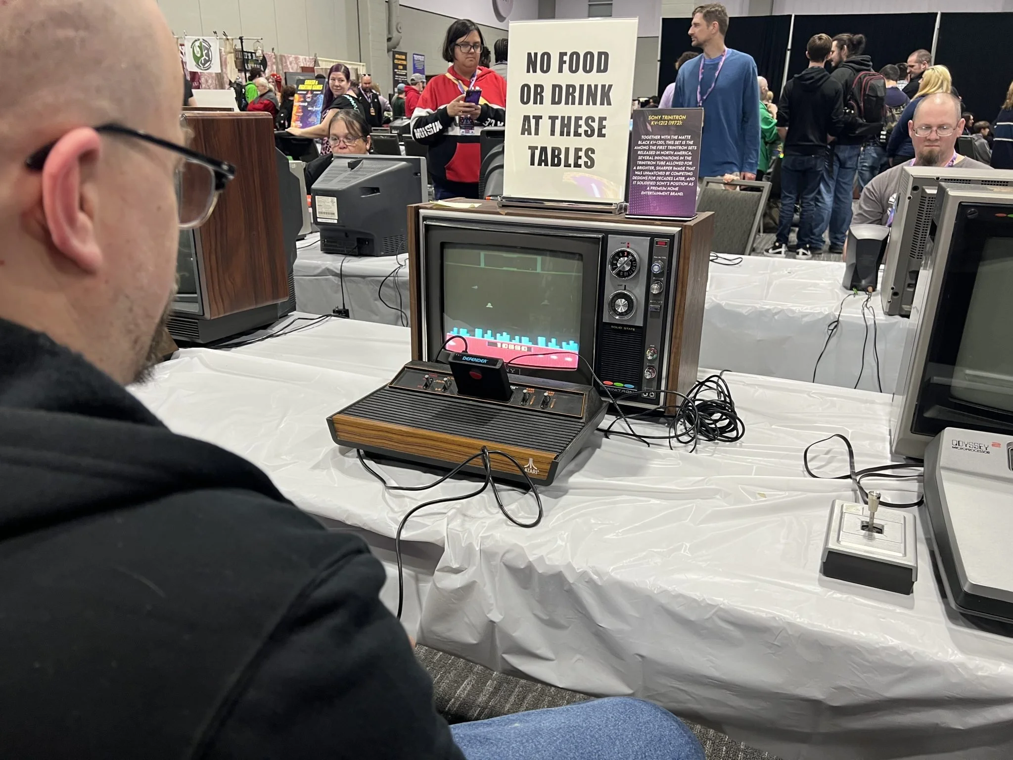 A person is playing an old-school vintage arcade game at Retro Game Con with a crowd of people in the background.