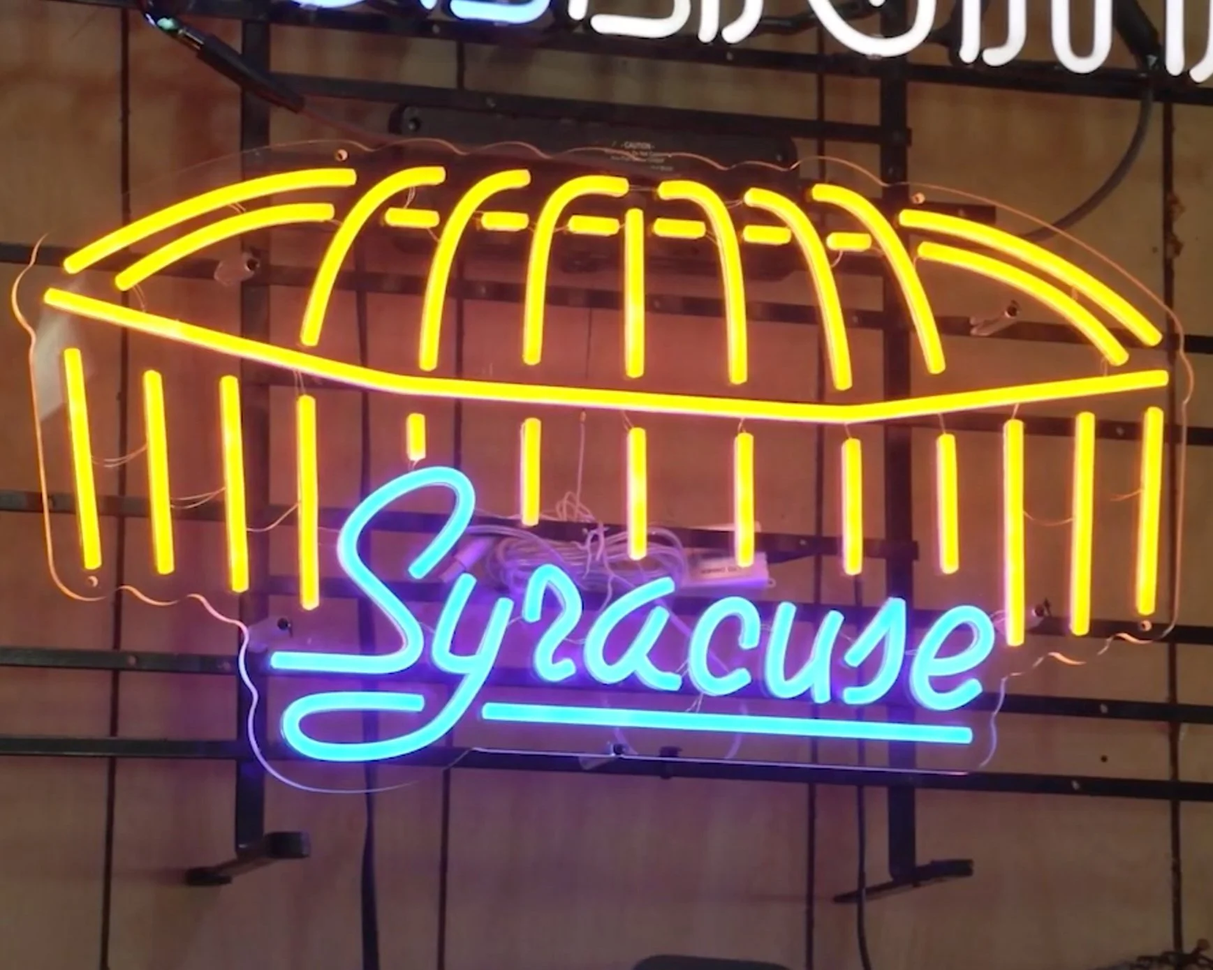Orange and blue neon sign of the Carrier Dome with "Syracuse" in blue below.