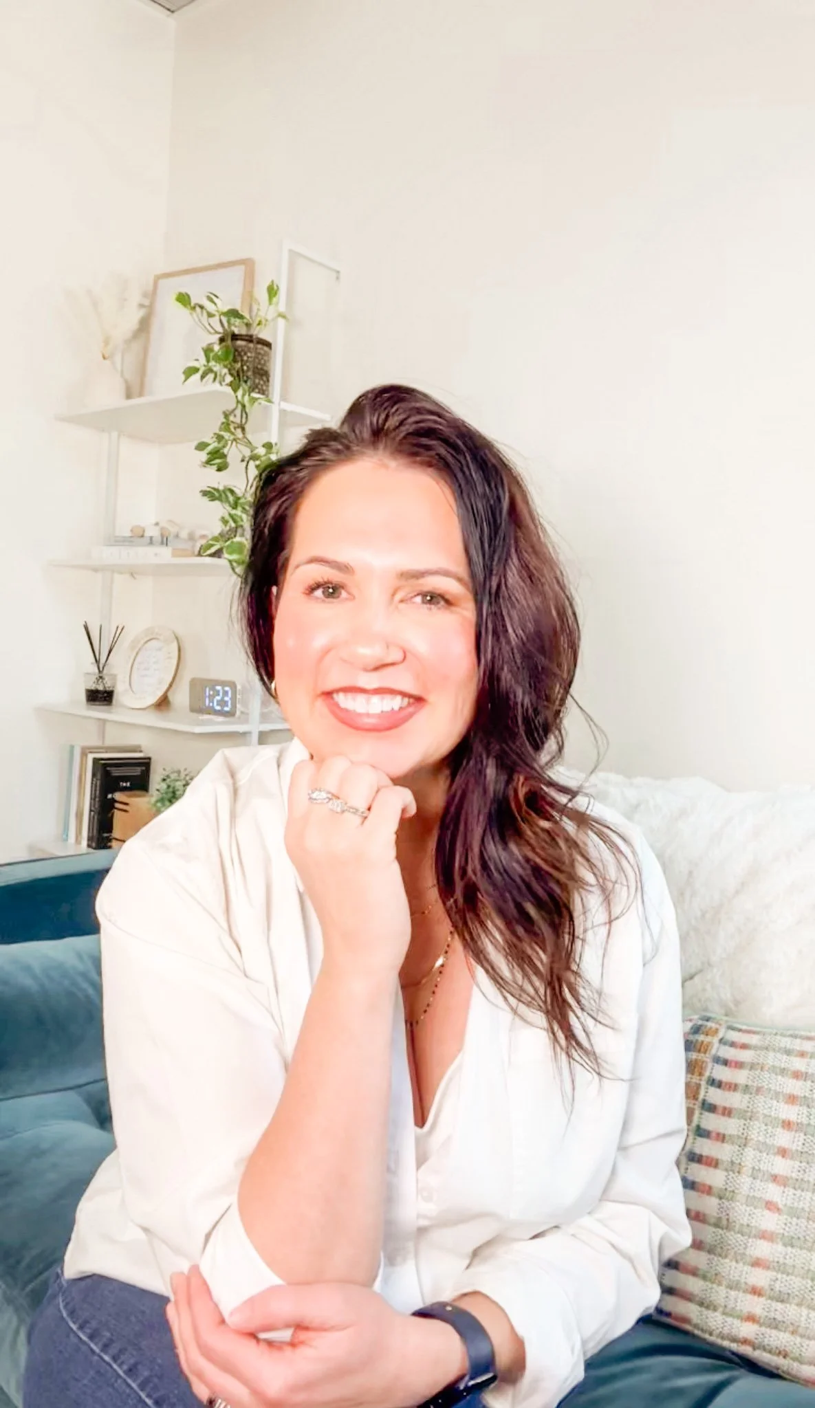 A woman smiling outdoors by a body of water during sunset.