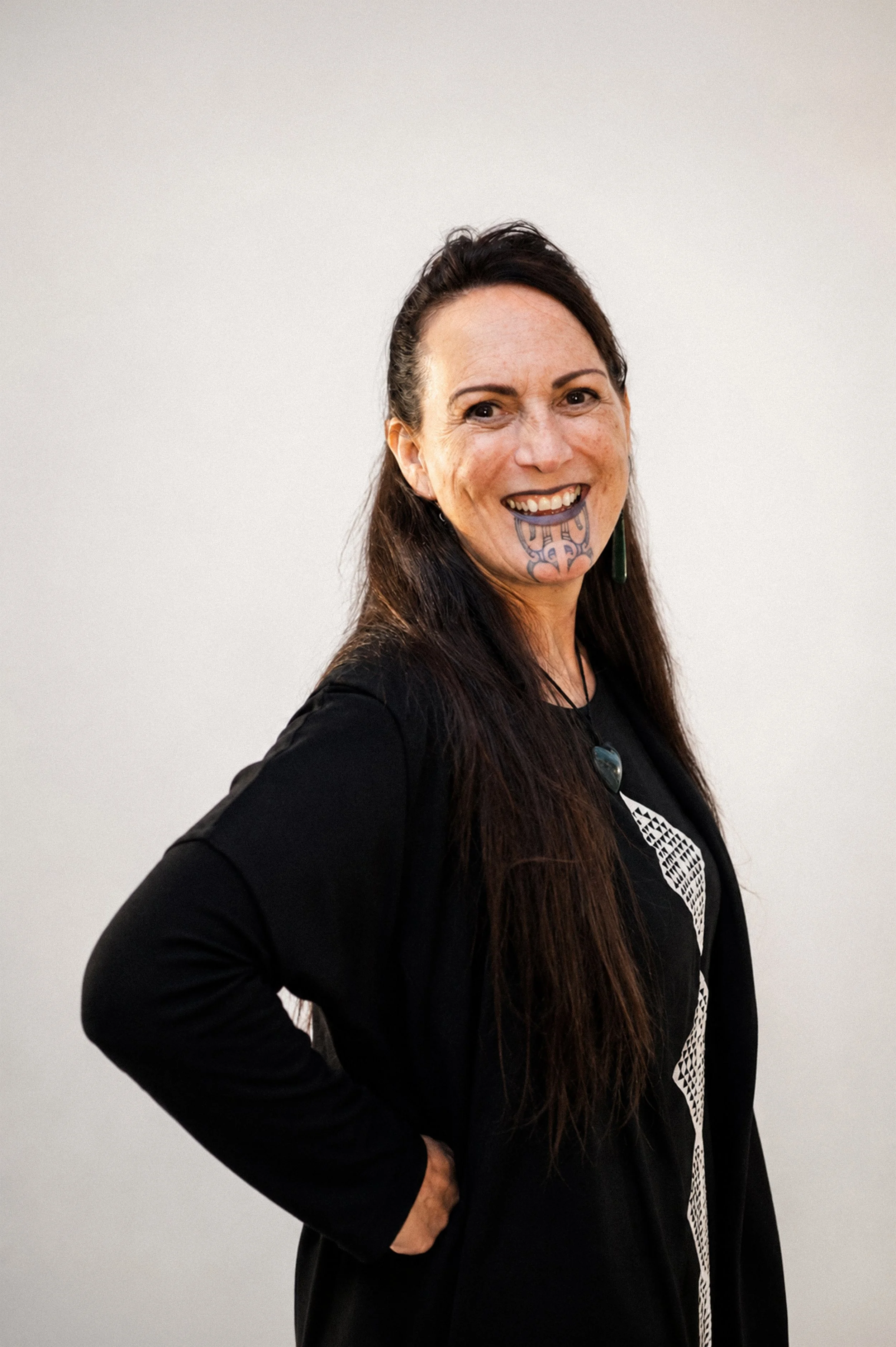 Nicky Birch, Pou Kōrero, stands in front of a white background. 