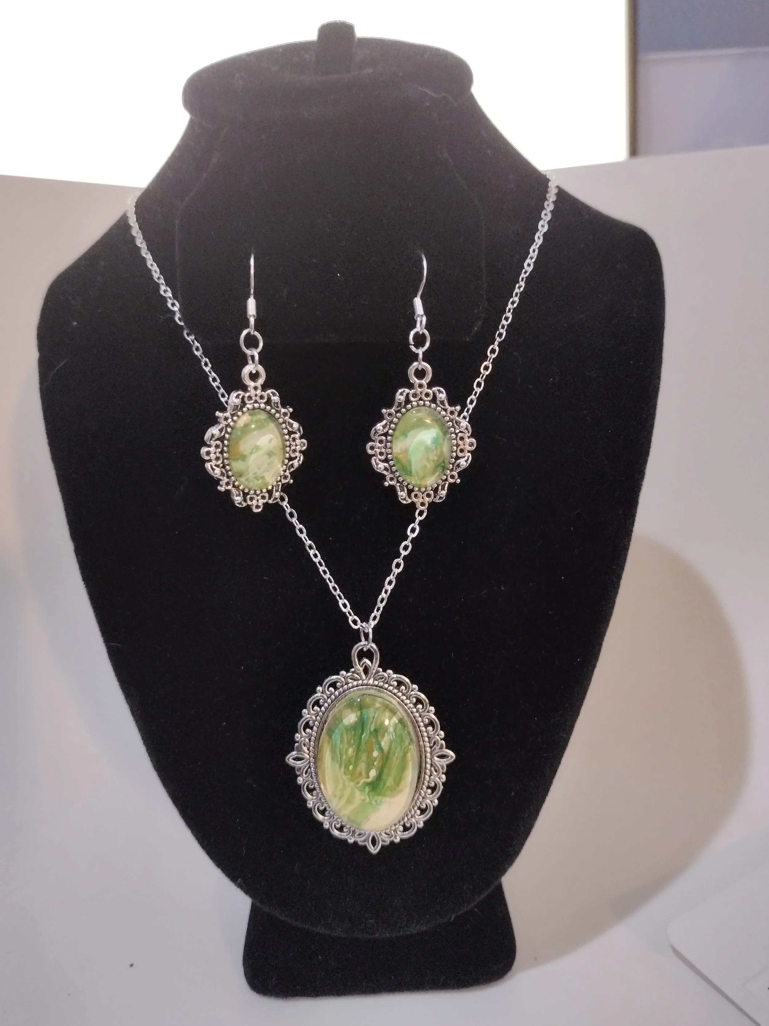 What begins as paint flowing beyond the edge of a canvas becomes something entirely new. This handcrafted necklace and earring set features an original acrylic paint skin, carefully preserved beneath glass cabochons to showcase its delicate swirls of