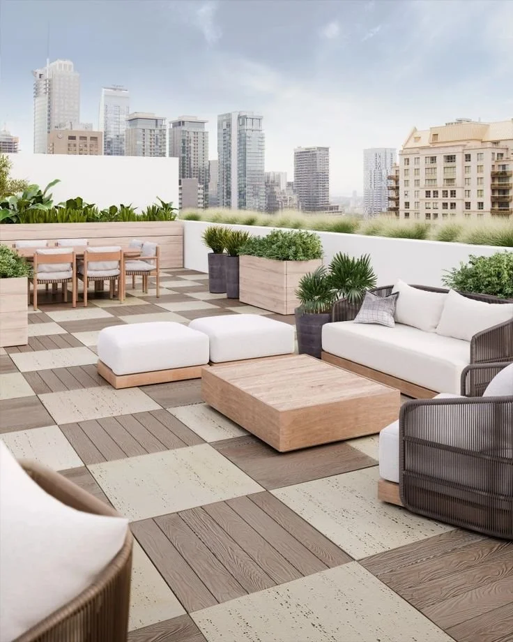 Rooftop terrace with outdoor seating, potted plants, and a city skyline view with tall buildings.