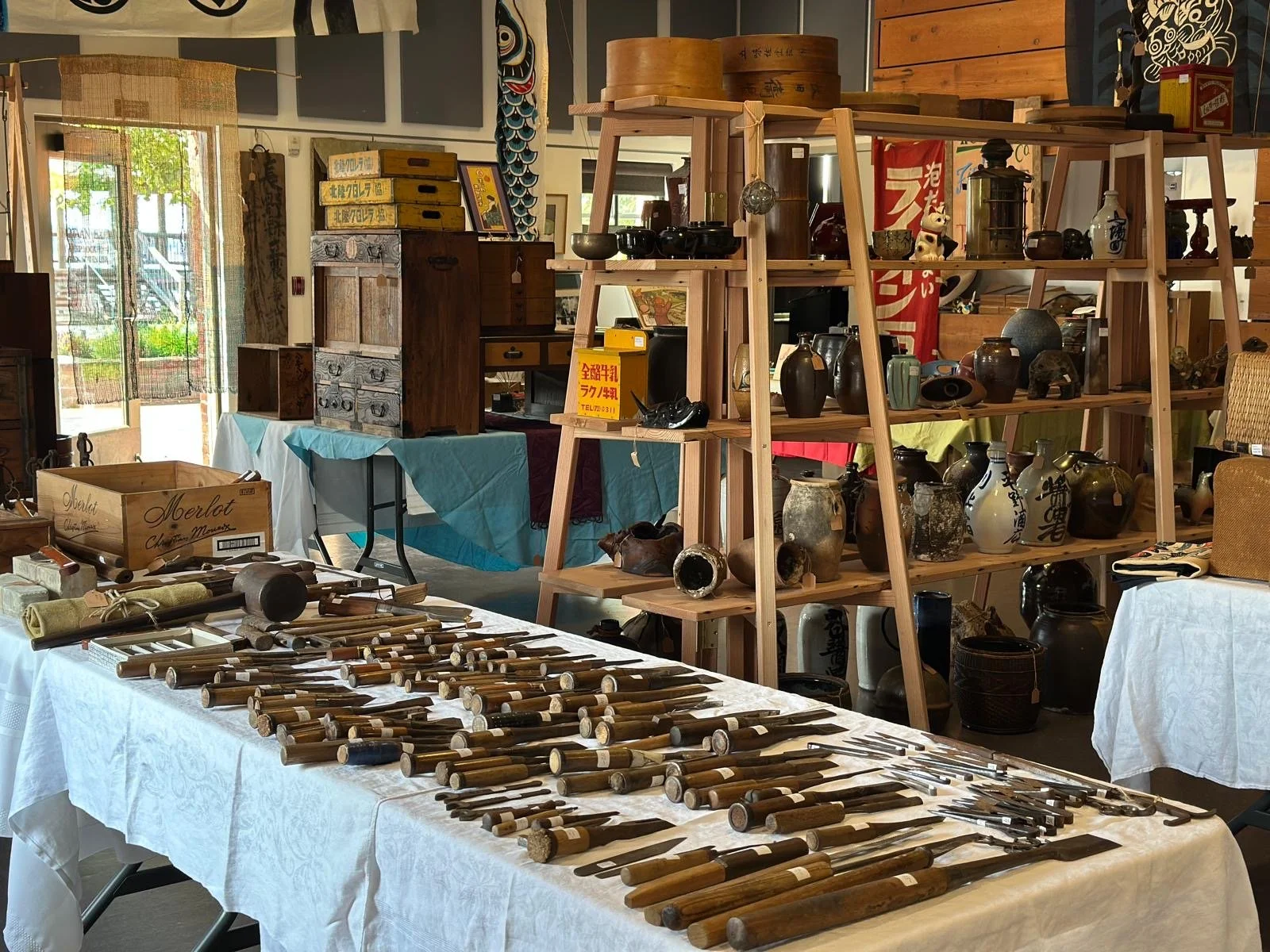 Curated display of Japanese antique woodworking tools, ceramics, and storage boxes arranged for a seasonal pop-up exhibition, emphasizing everyday objects shaped by use and craftsmanship.