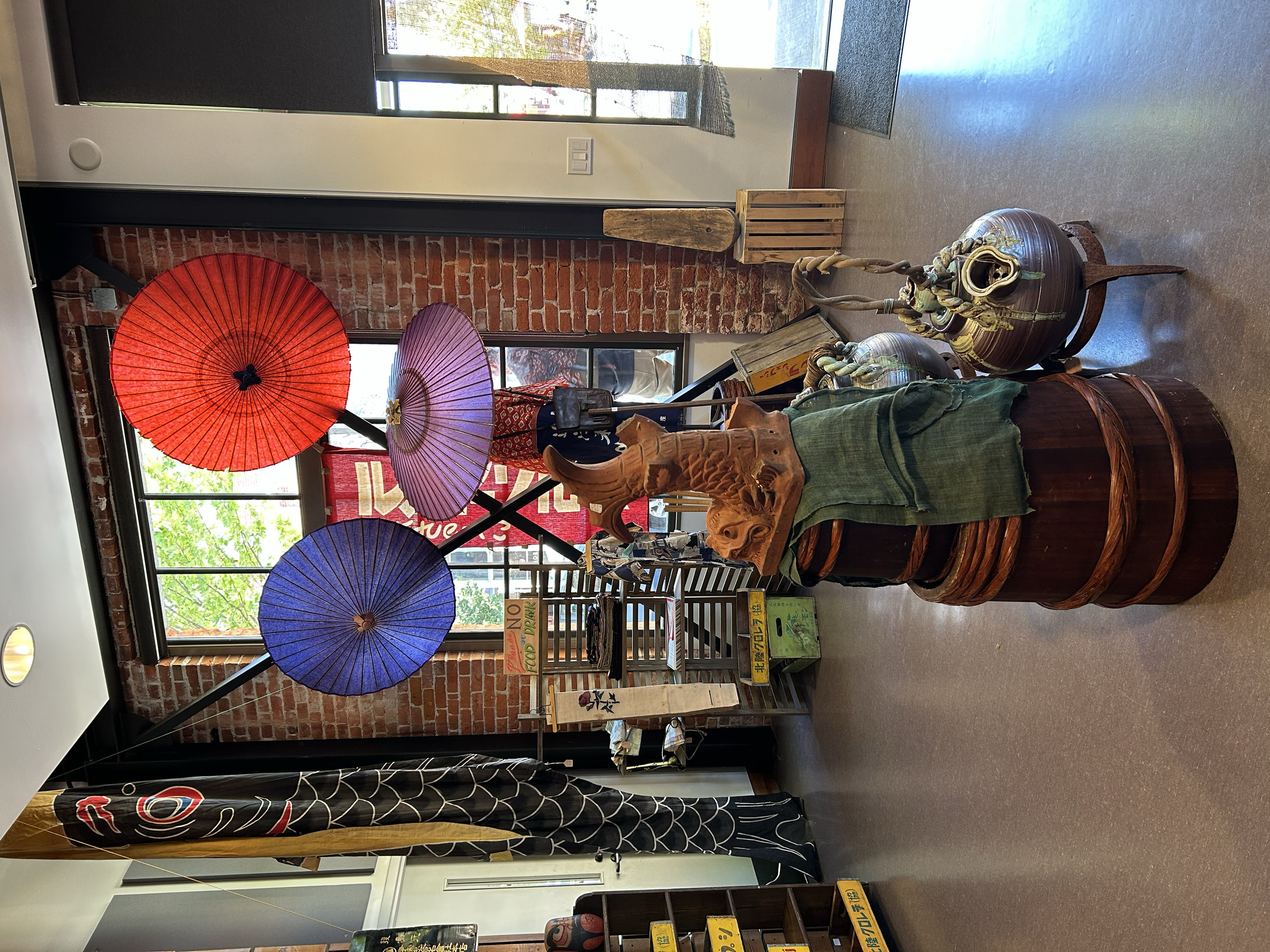 Central display featuring traditional Japanese paper parasols alongside sculptural wooden and ceramic objects, arranged as a focal installation within the pop-up space.