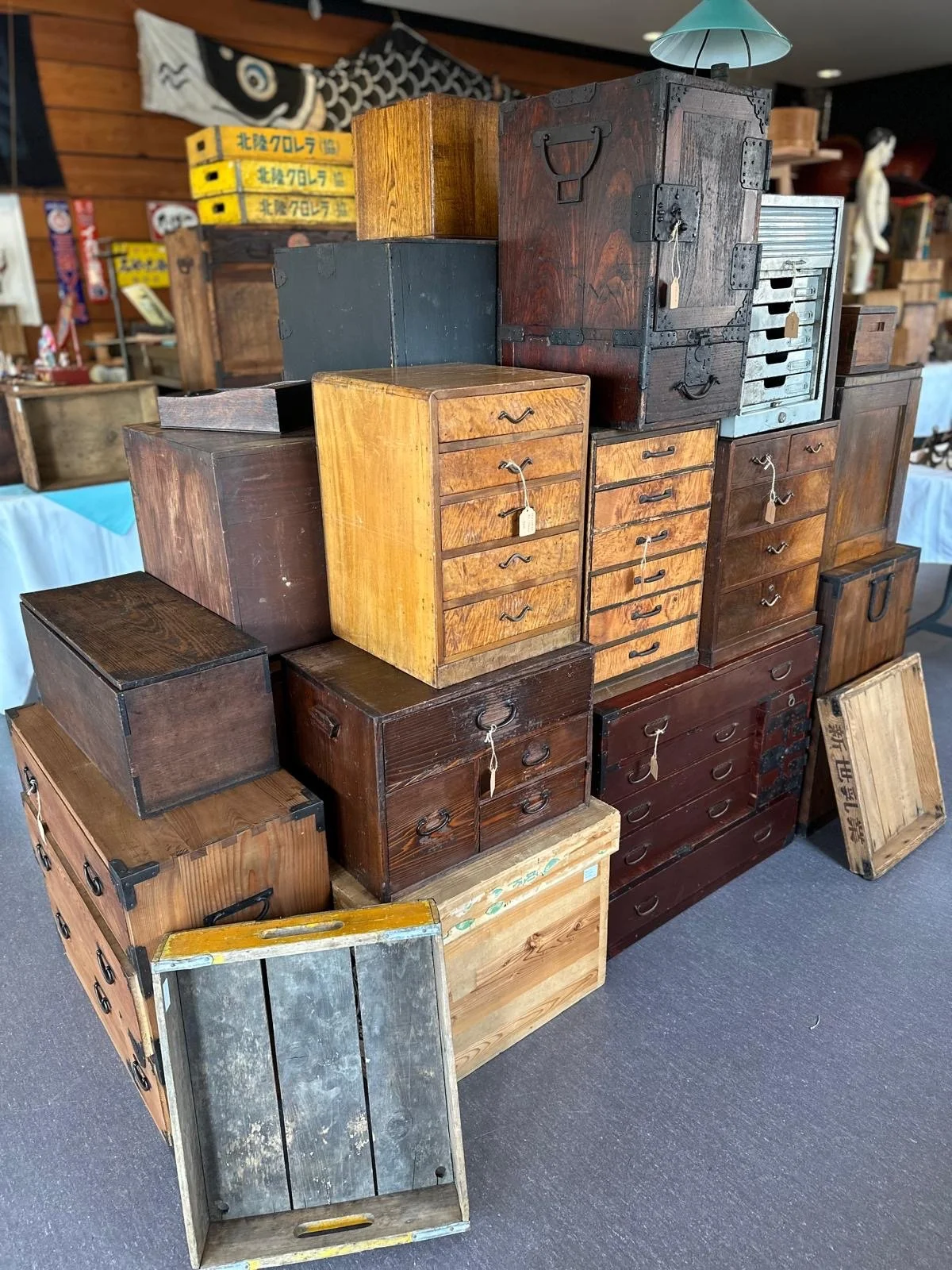 Stacked arrangement of Japanese tansu chests and wooden storage boxes, showing varied woods, iron hardware, and surface patina from long-term use.