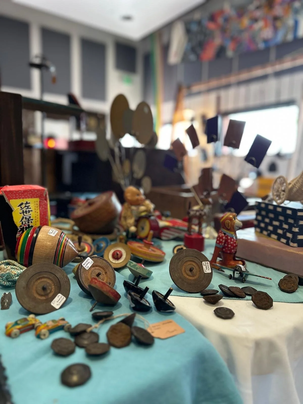 Close view of Japanese antique toys and ephemera including spinning tops, small figures, and paper items, arranged to highlight playful design and age patina.