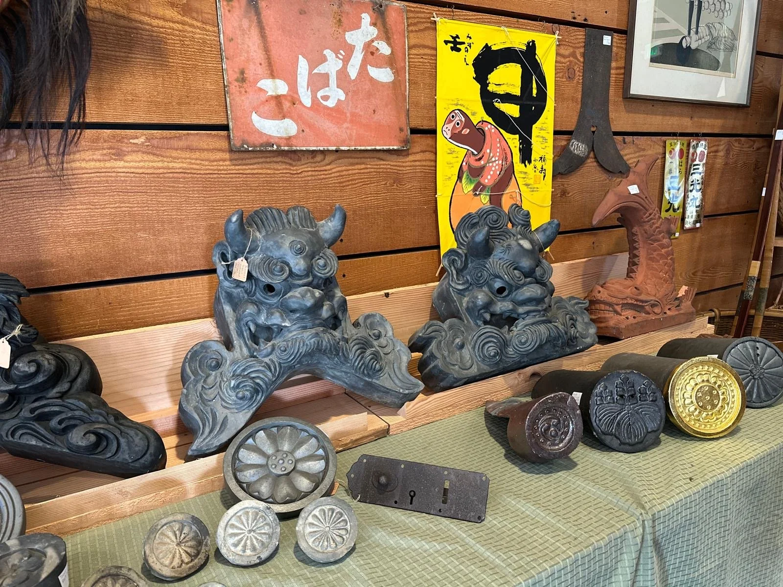 Selection of antique Japanese roof tiles and shishi guardian figures, originally used as architectural elements, presented with visible wear from outdoor use.