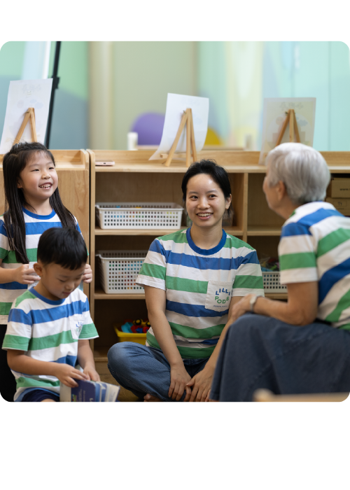 Young children and a caregiver engaged in conversation in a classroom setting.