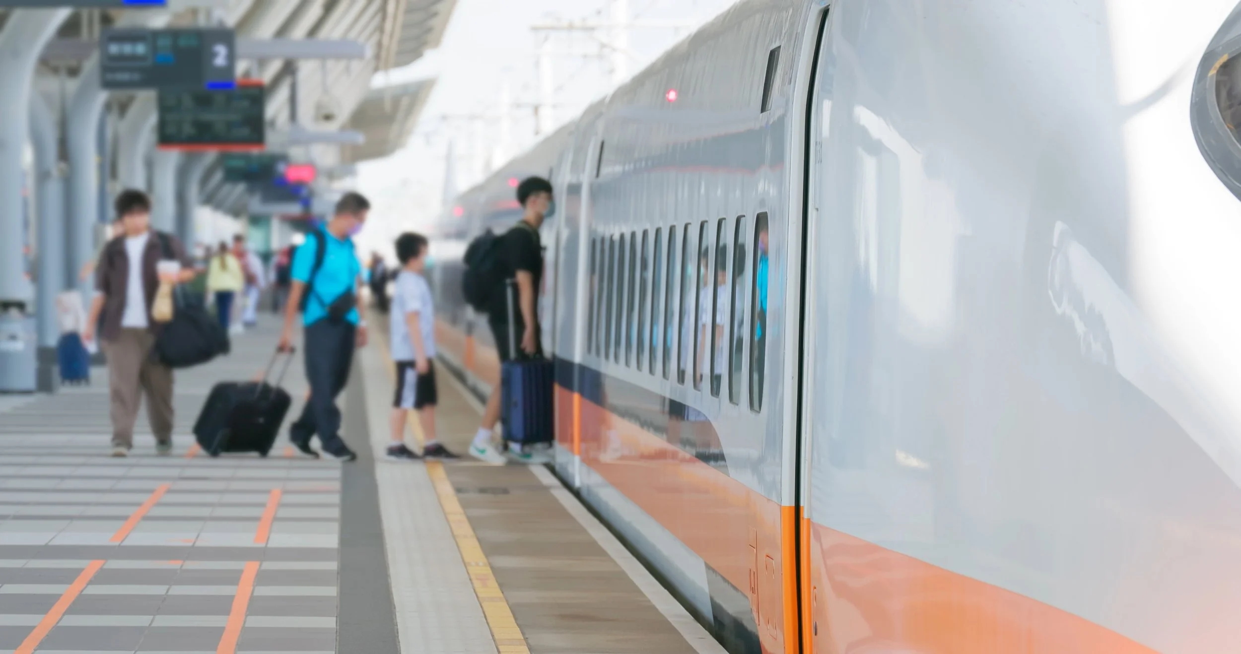 Passengers boarding a modern high-speed train at a train station platform.