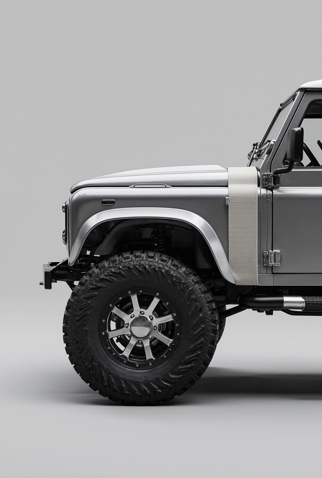 Front half of a silver off-road vehicle with large tires and rugged design, isolated on a plain background.