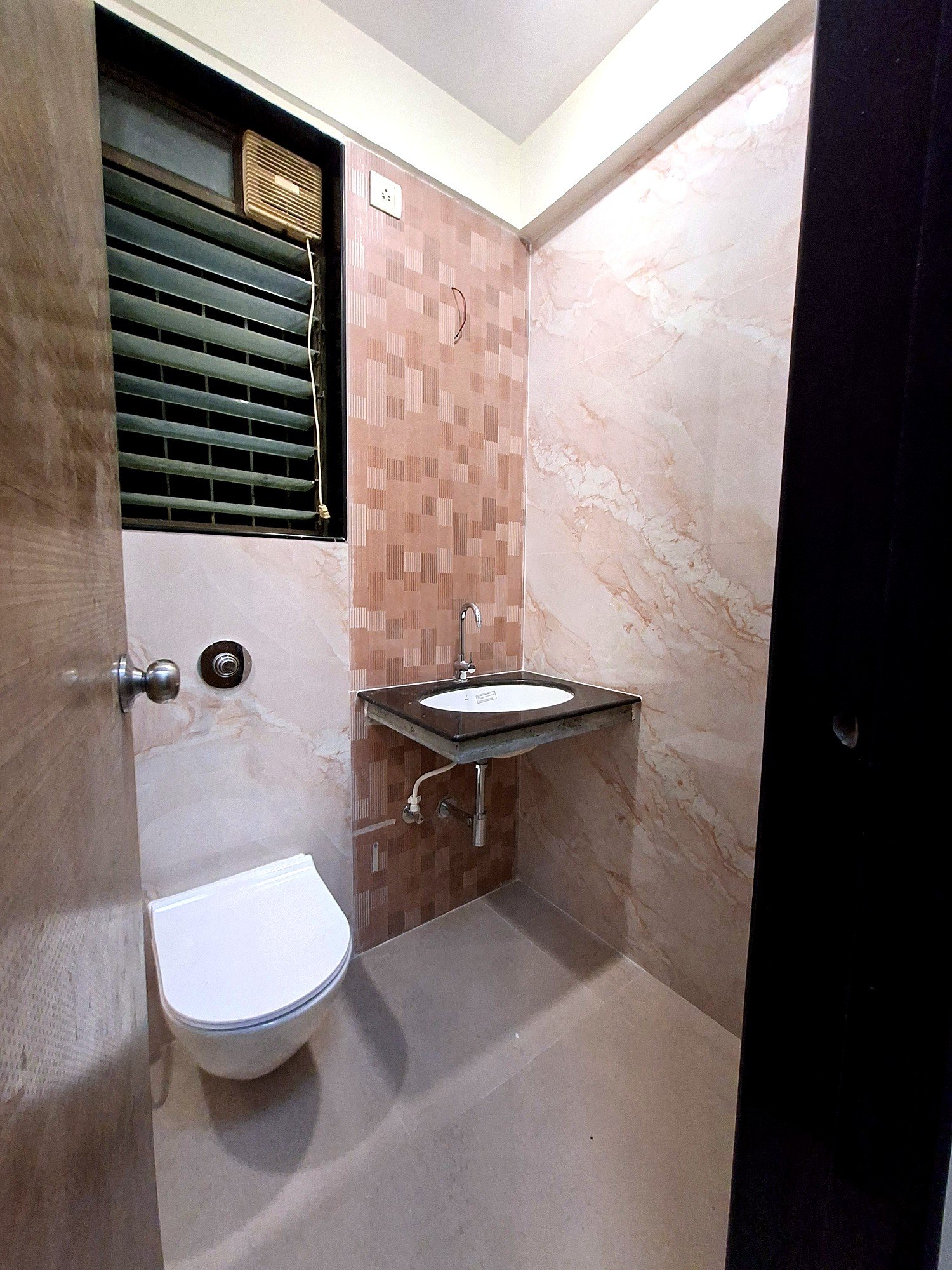 Renovated bathroom with wall-mounted WC and marble finish at Lake Pleasant Powai 2BHK