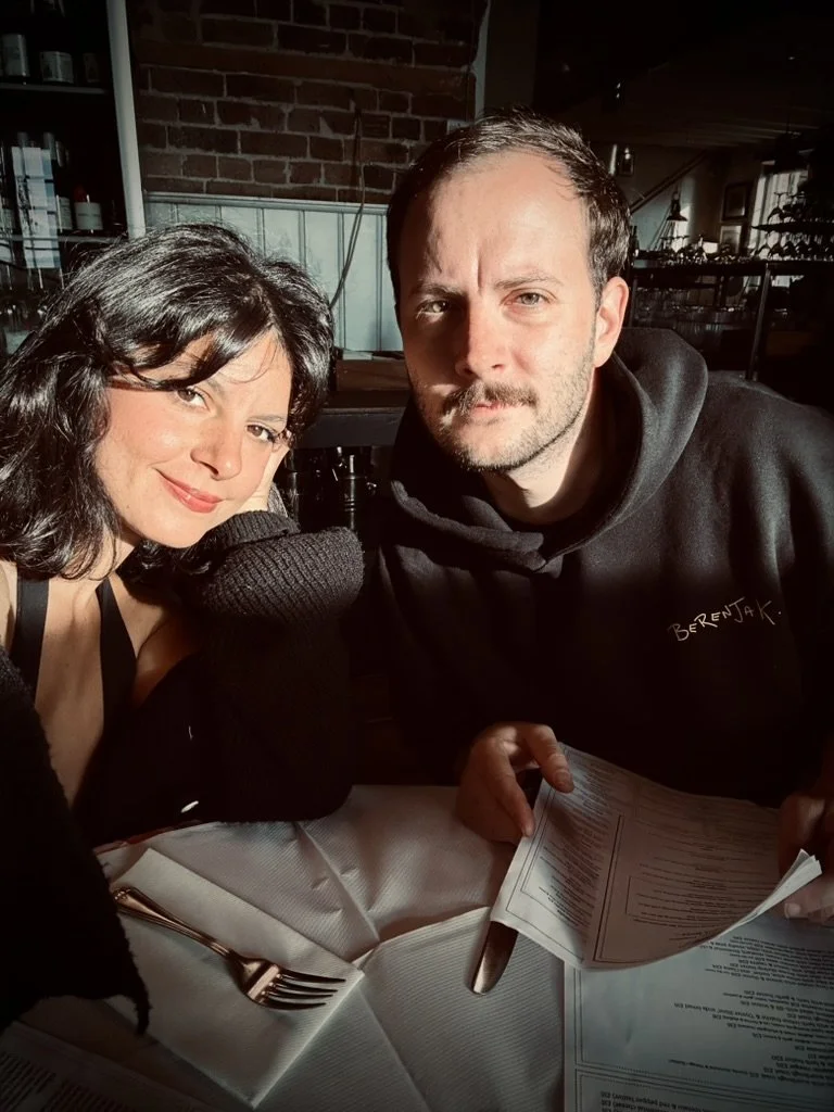 Founders of Margate Manor, A woman and man sitting at a restaurant table, smiling at the camera. The woman has dark hair  while the man has short hair and a beard holding a menu.