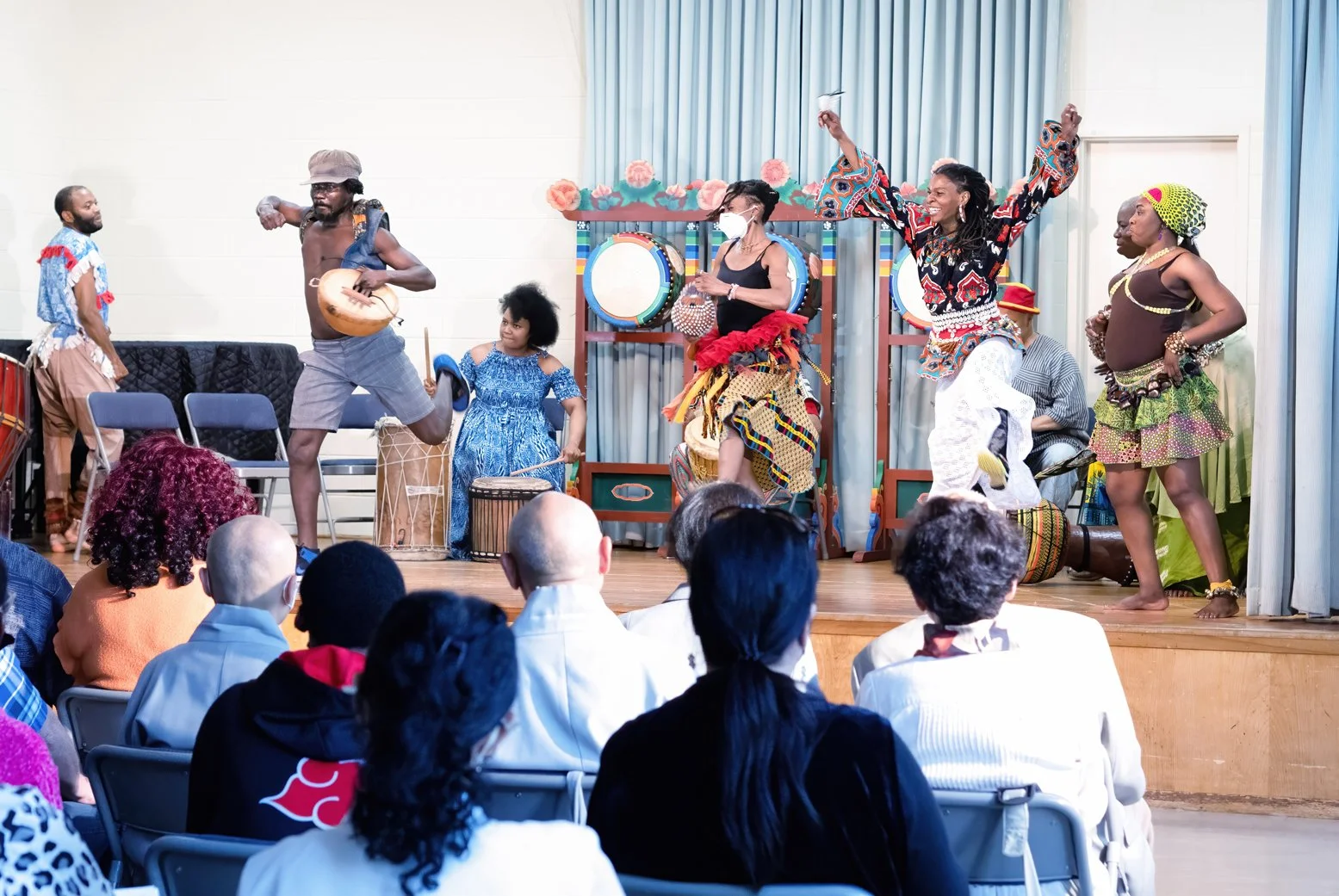 People performing cultural dance on stage with audience watching.