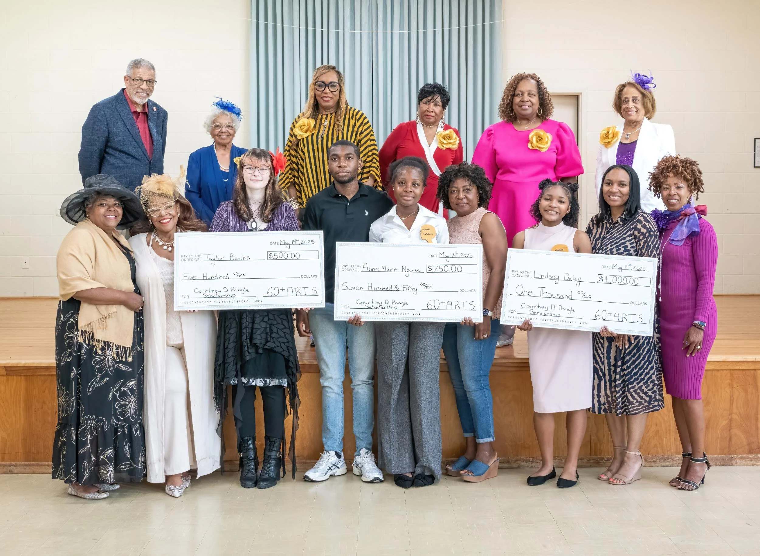 Group of people on a stage holding oversized checks and awards, celebrating scholarship recipients. There are both men and women of diverse ages and backgrounds, dressed in colorful and formal attire.