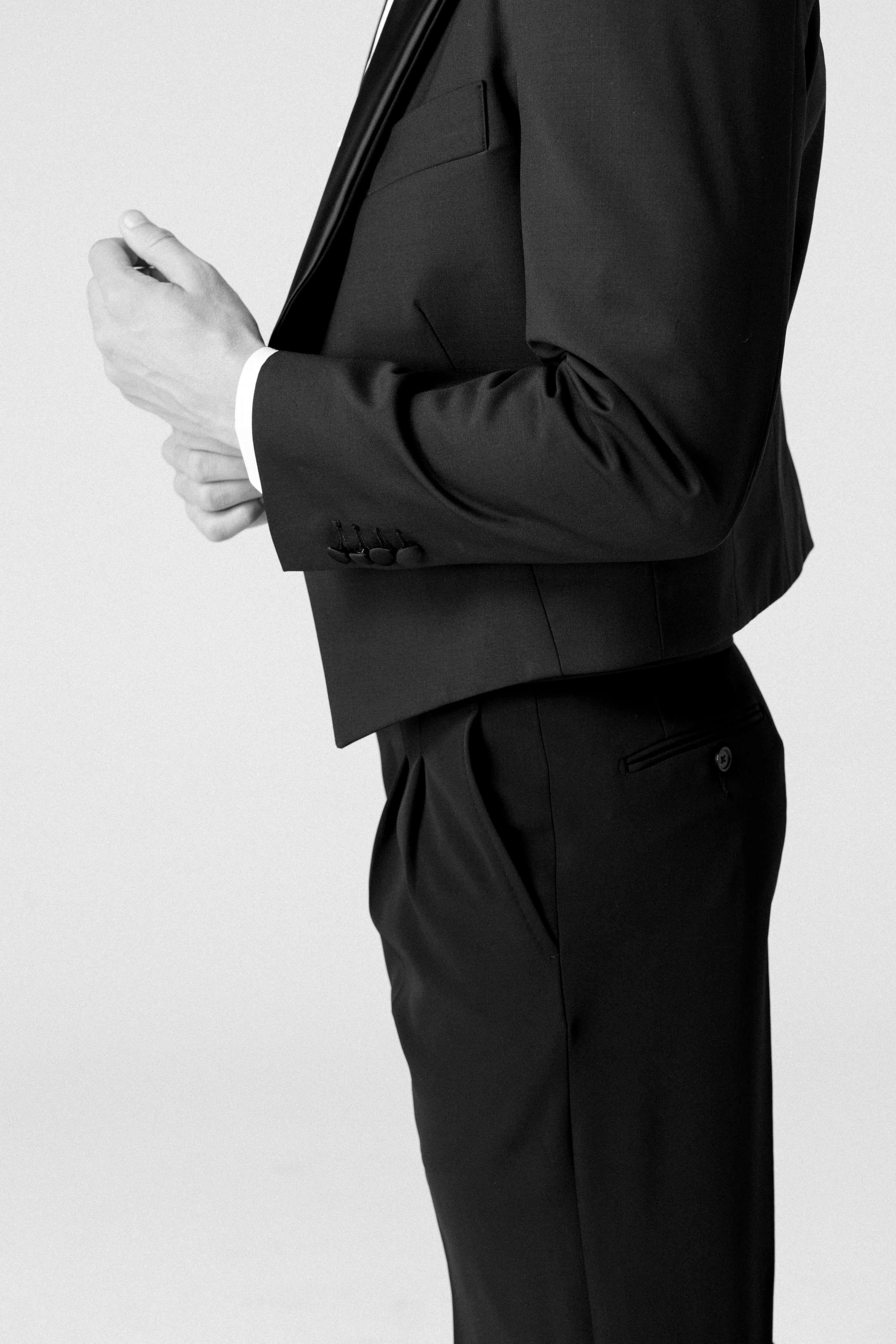 Uomo in completo nero che guarda il suo smartphone, in un'ambientazione minimalista.