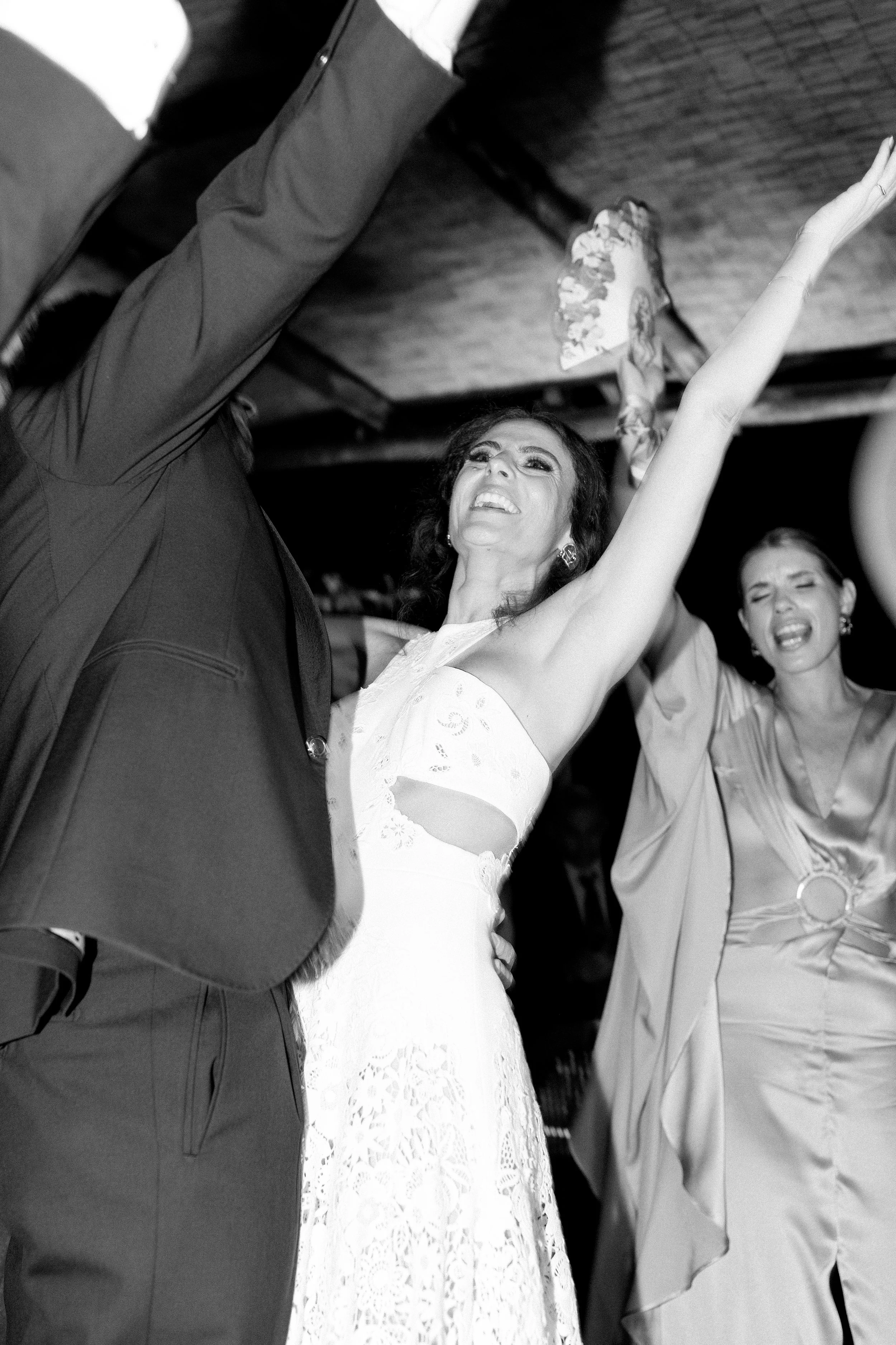 Donne che ballano e sorridono, una donna al centro indossa un vestito bianco con dettagli ricamati