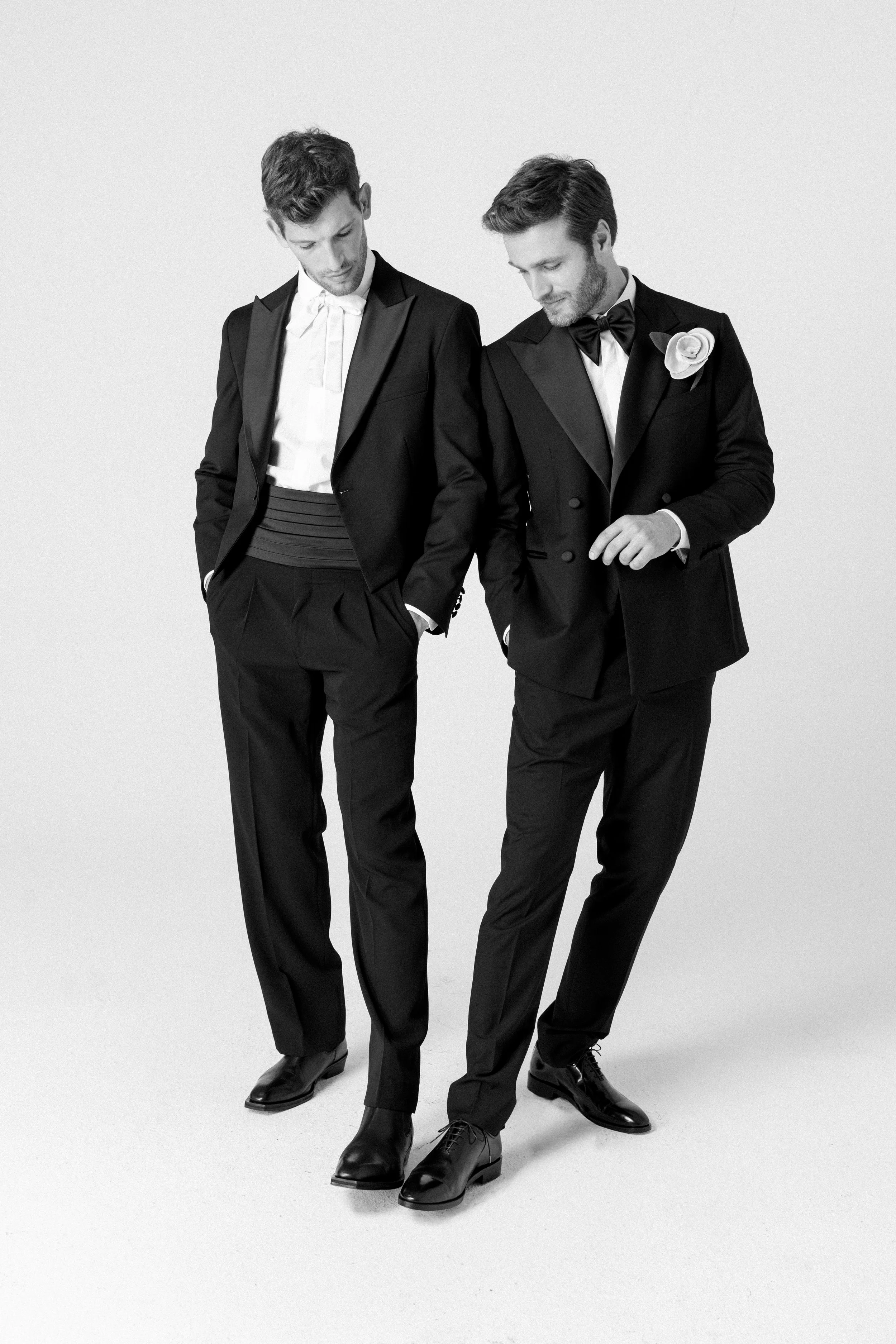 Due uomini in abiti eleganti, uno con fiore sulla giacca, in bianco e nero.
