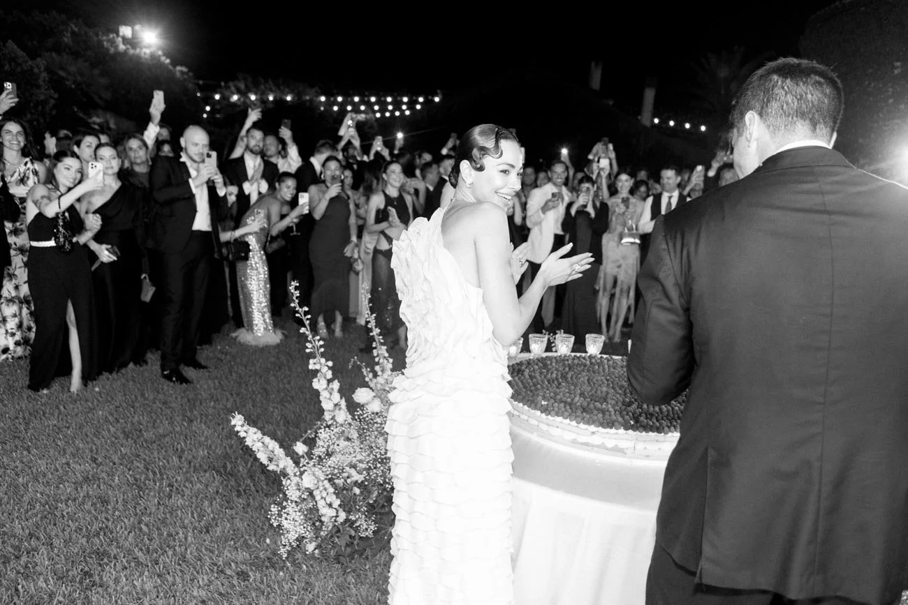 Una coppia di sposi che festeggia con un grande gruppo di amici durante una cerimonia di matrimonio all'aperto di notte.