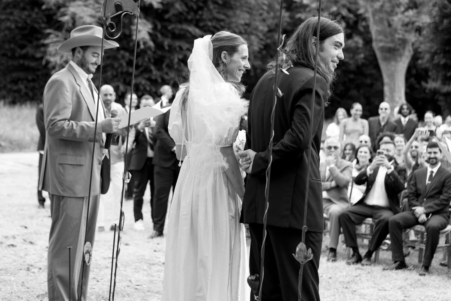 Una coppia si sposa in una cerimonia all'aperto, circondata da amici e parenti, in un ambiente naturale.