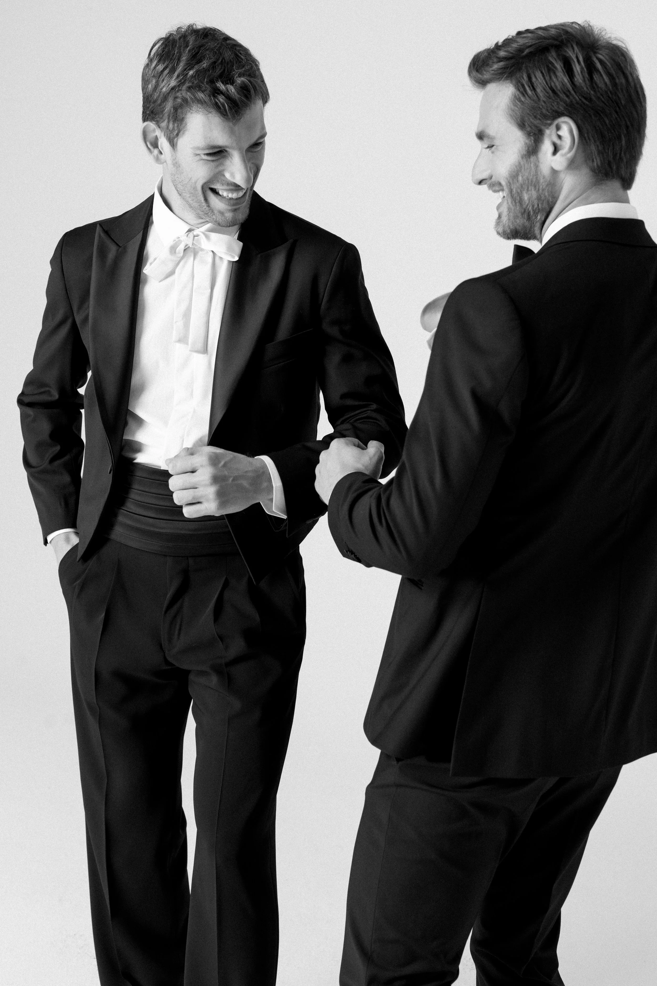 Due uomini in abiti formali si stringono la mano in un abbraccio amichevole, sorridendo.