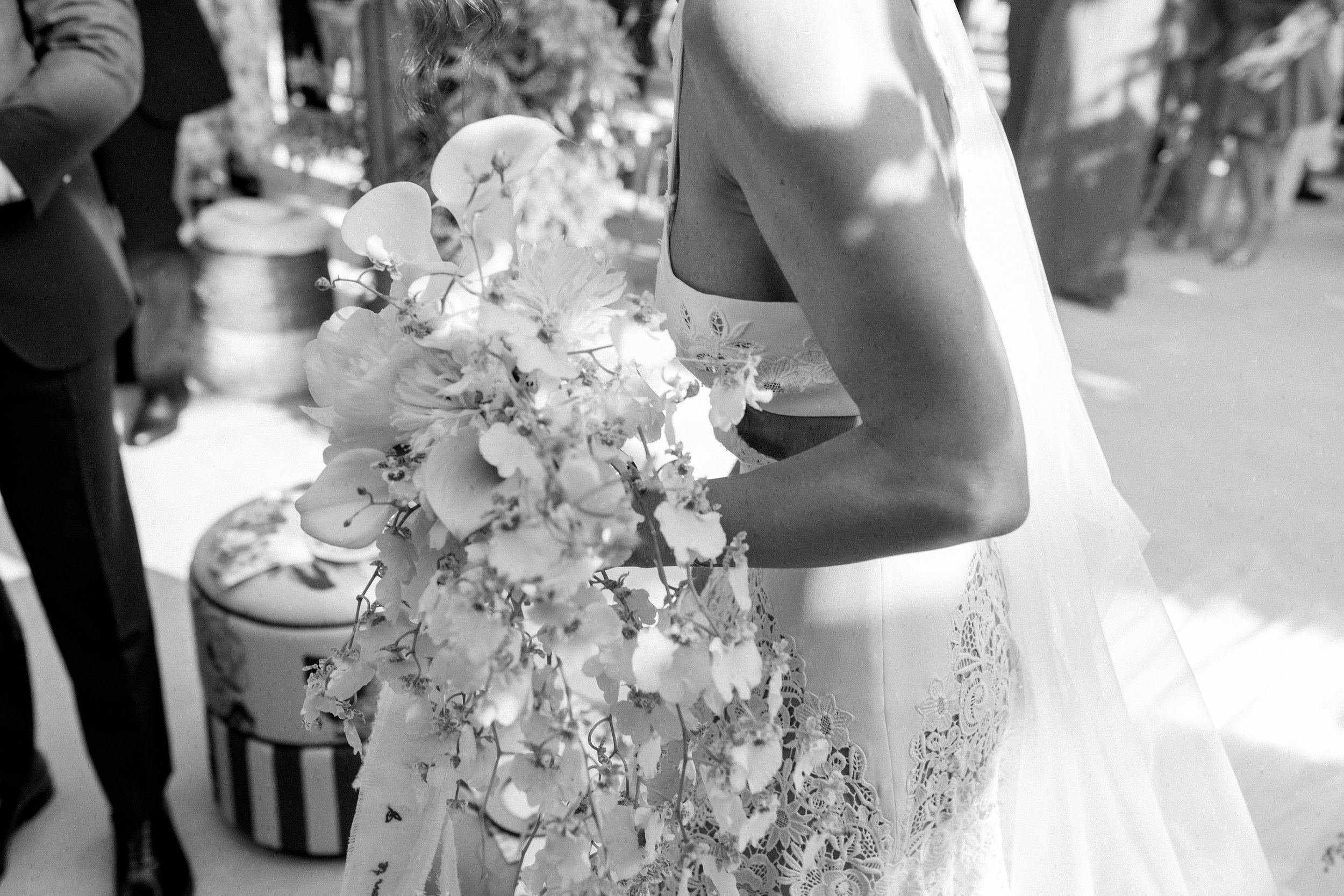 Una sposa tiene in mano un bouquet di fiori, indossa un abito da sposa in pizzo e un velo, ed è in un contesto di matrimonio o evento simile.