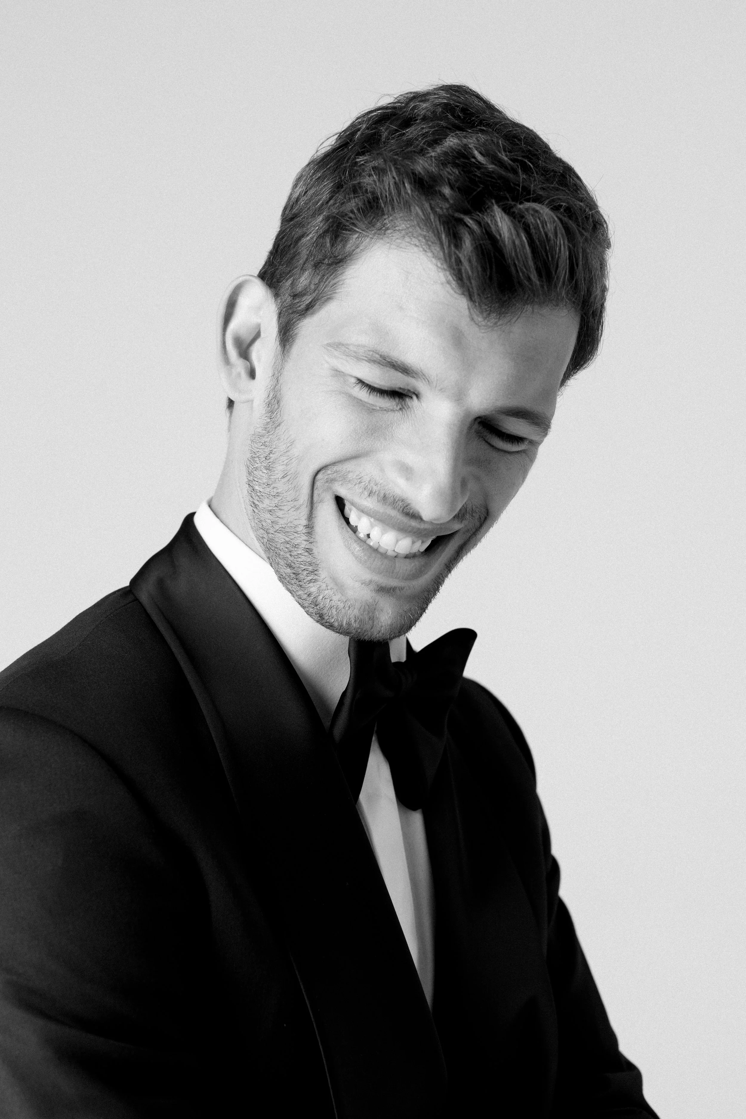 Ritratto di un uomo sorridente vestito formalmente con smoking e papillon in bianco e nero