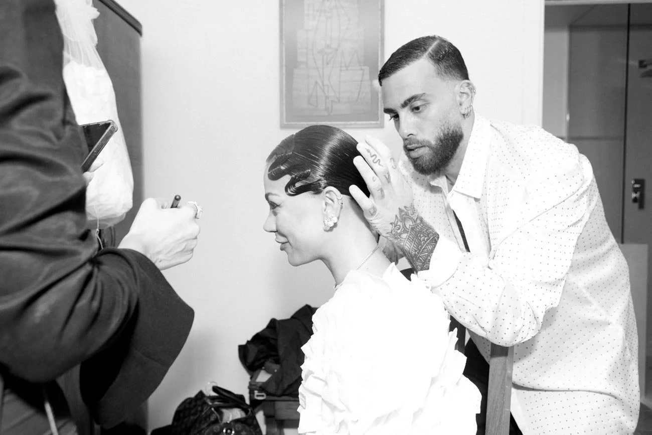 Uno stylist sta sistemando i capelli a una modella prima di un servizio fotografico.