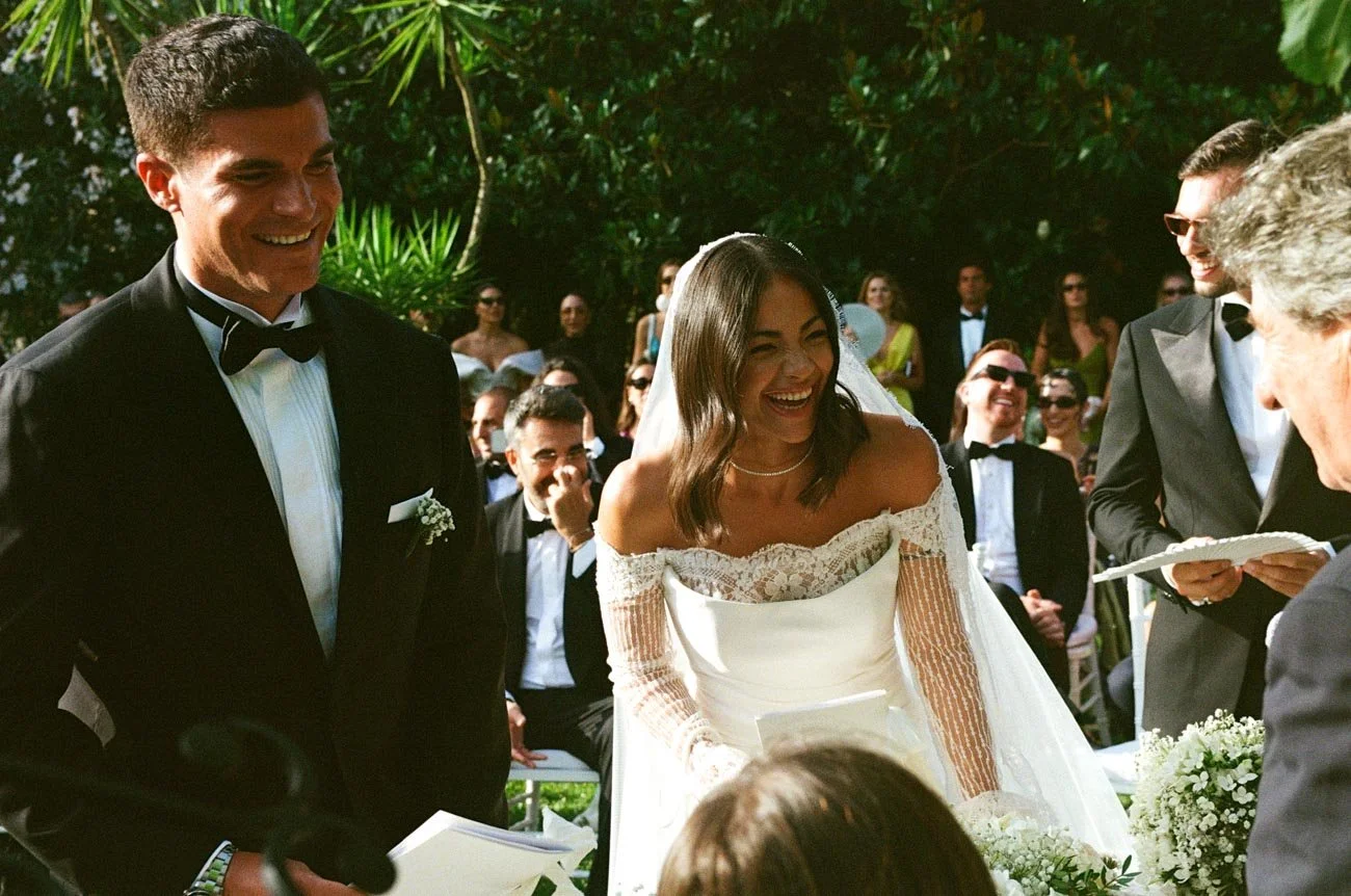 Sposi felici durante il matrimonio, circondati da amici in un giardino verde.