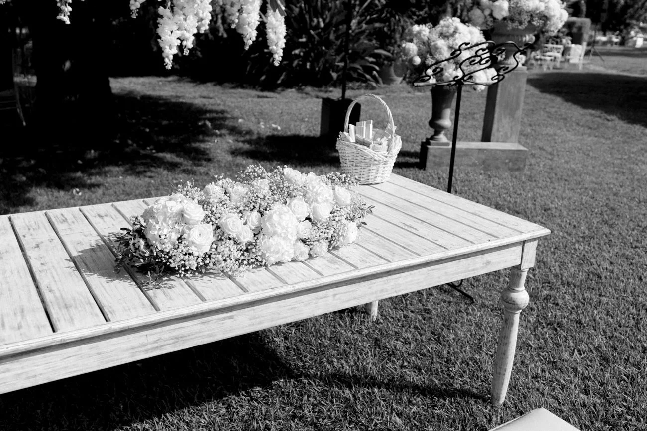 Una sedia di legno con un mazzo di fiori bianchi e una cesta bianca su un tavolo all'aperto in giardino