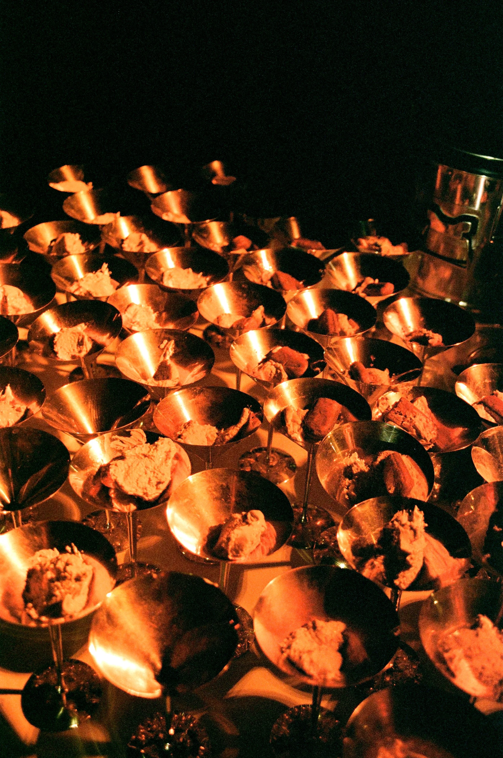 Coppe di gelato o dessert in ciotole di metallo, illuminate da luci calde