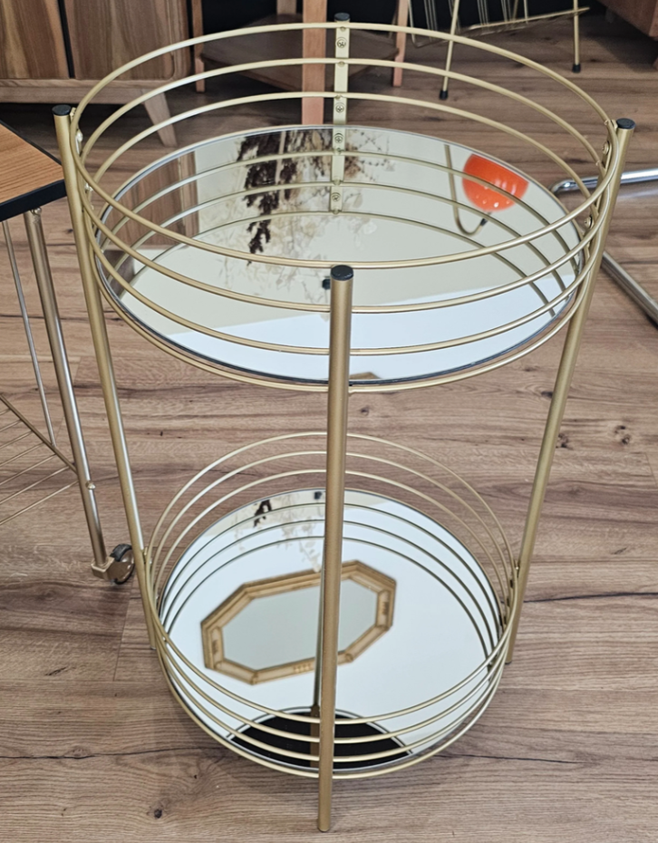 Table de service avec deux plateaux en miroir entourés de cercles métalliques dorés, sur un sol en bois