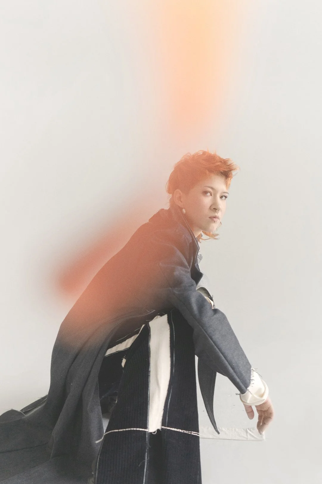 Hockende Person von der Seite, blick in die Kamera. Sie trägt ein Outfit Julia Schürmann - von raum6.7