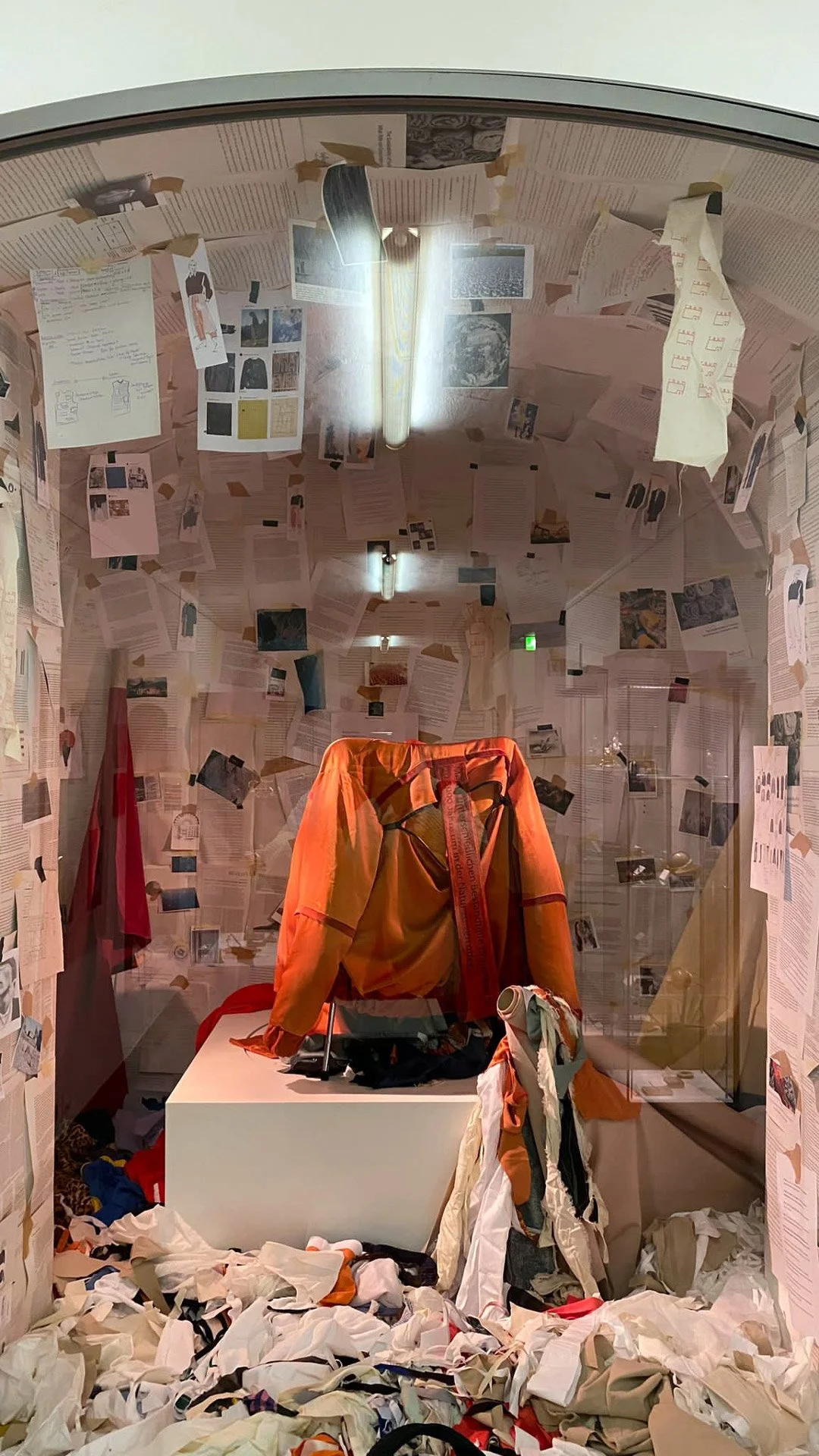 Rauminstallation aus einem Kleidungspbjetzt, SToffabfällen und vielen papierausdrucken mit Text und Bild