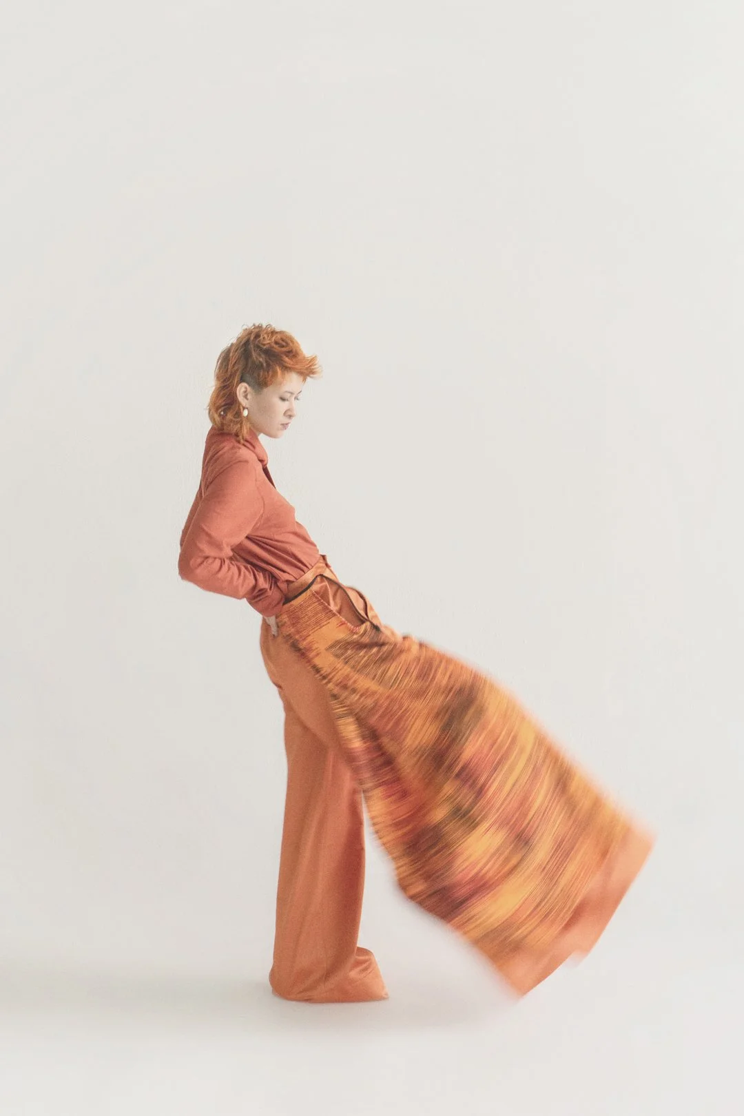 Person in komplett orangenen Outfit von Julia Schürmann - raum6.7 und orangenen Haaren. Das Bein ist in bewegung und dadurch unscharf.