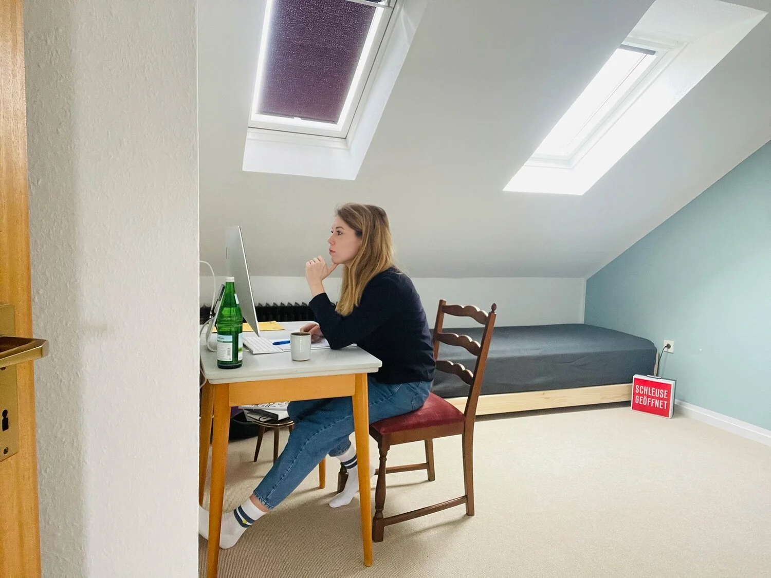 Superidee Mitarbeiterin Sarah sitzt im Home Office in einem Dachgeschosszimmer vor ihrem Computer.