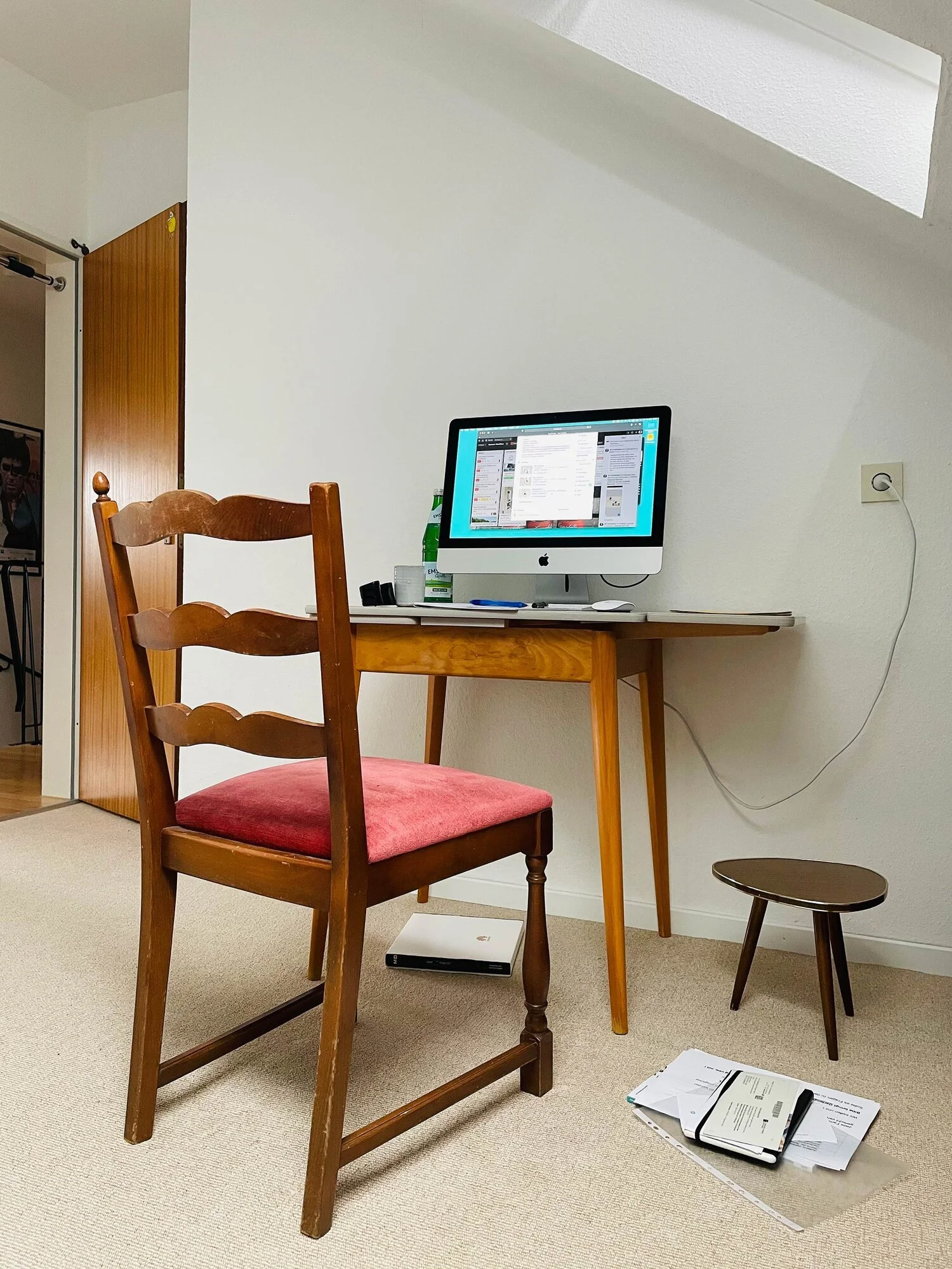 Arbeitsplatz mit Holztisch und Stuhl, einem Computer und Beistelltisch im Dachgeschoss.