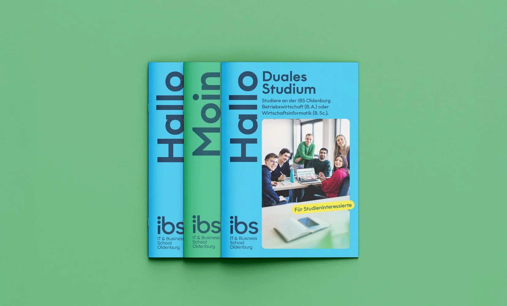 Drei Broschüren für das duale Studium am IBS Oldenburg, mit einem Foto einer Gruppe Studierender an einem Tisch, die an einem Laptop arbeiten, vor einem großen Fenster.