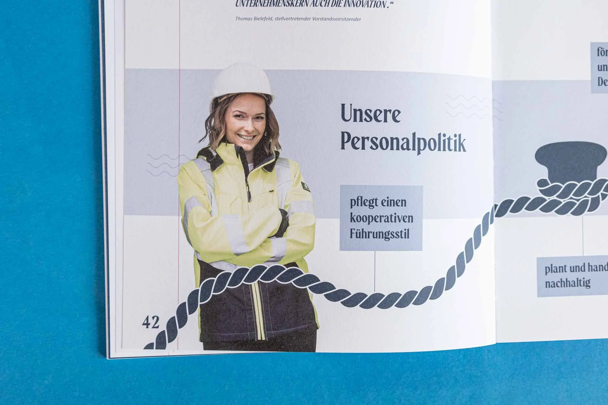Ein Poster mit einem Bild einer lachenden Frau in gelber Arbeitsjacke und Schutzhelm, das den Text "Unsere Personalpolitik" enthält.