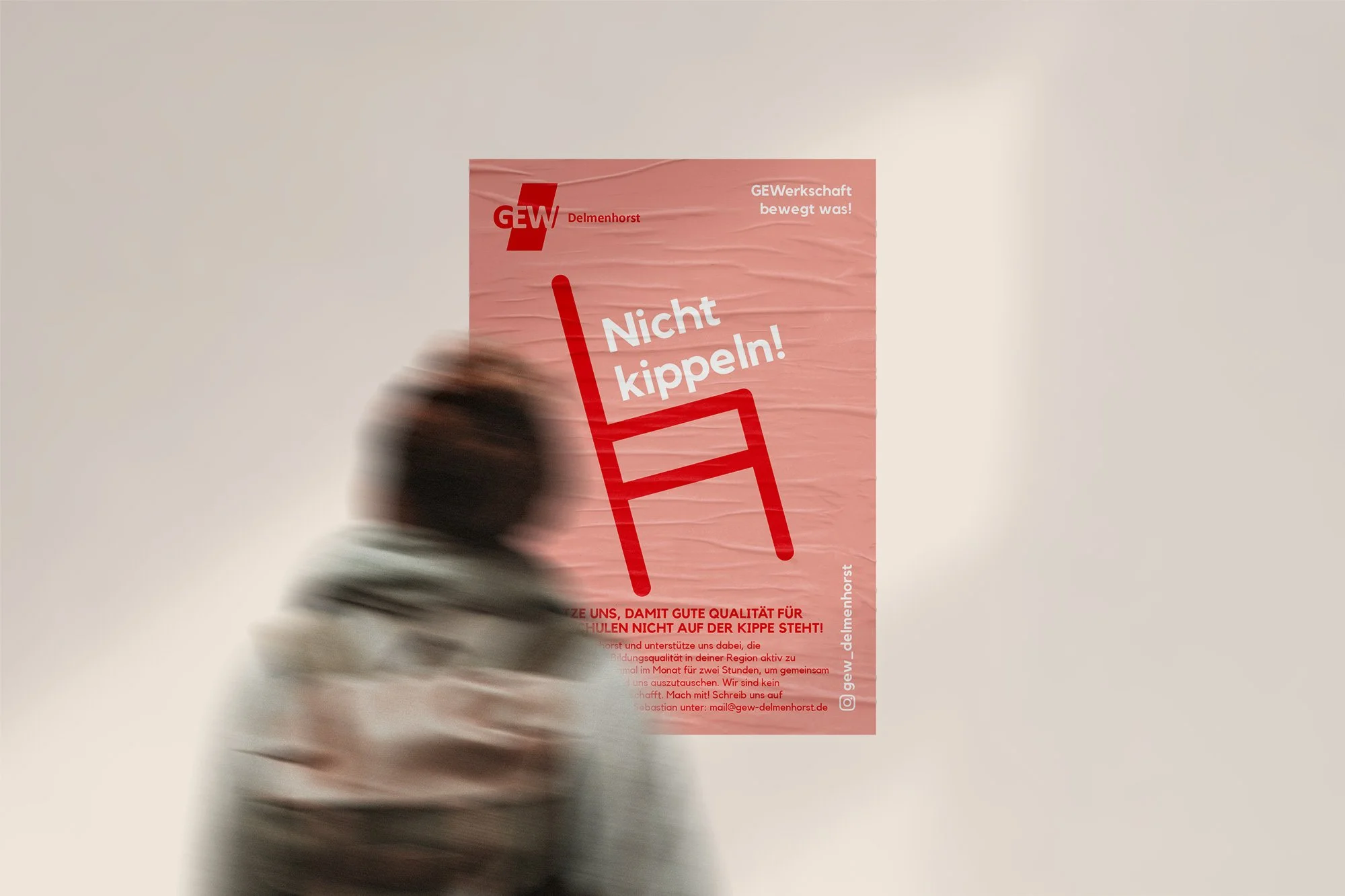 Eine Person, die mit deM Rücken Kamera steht und leicht verschwommen ist. Der Blick geht auf ein Plakat der GEW.