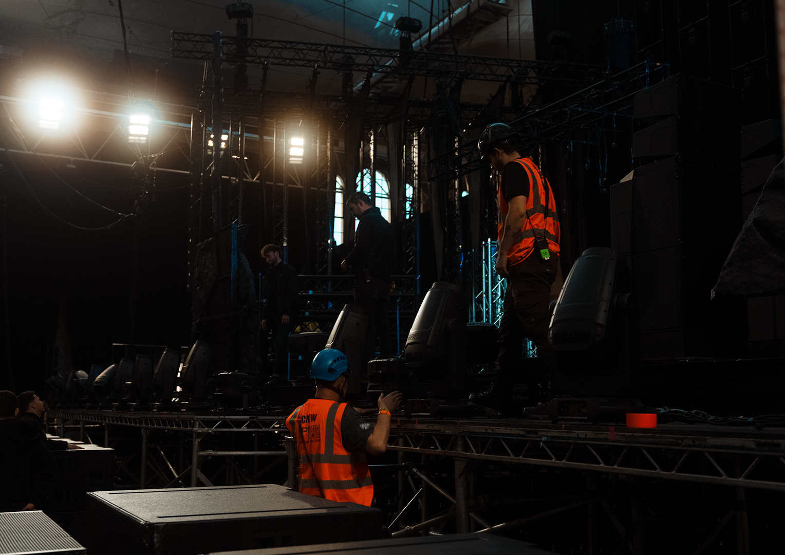 Stage crew preparing for a live concert, with workers adjusting equipment and lighting.