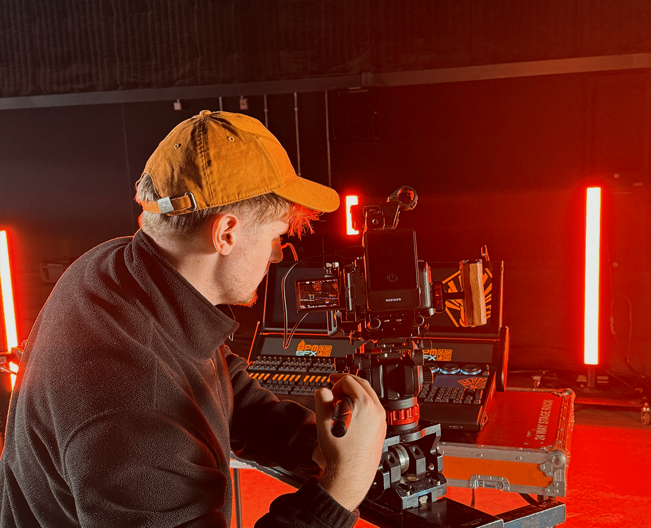 Person filming with professional camera in a dark studio with red lighting.