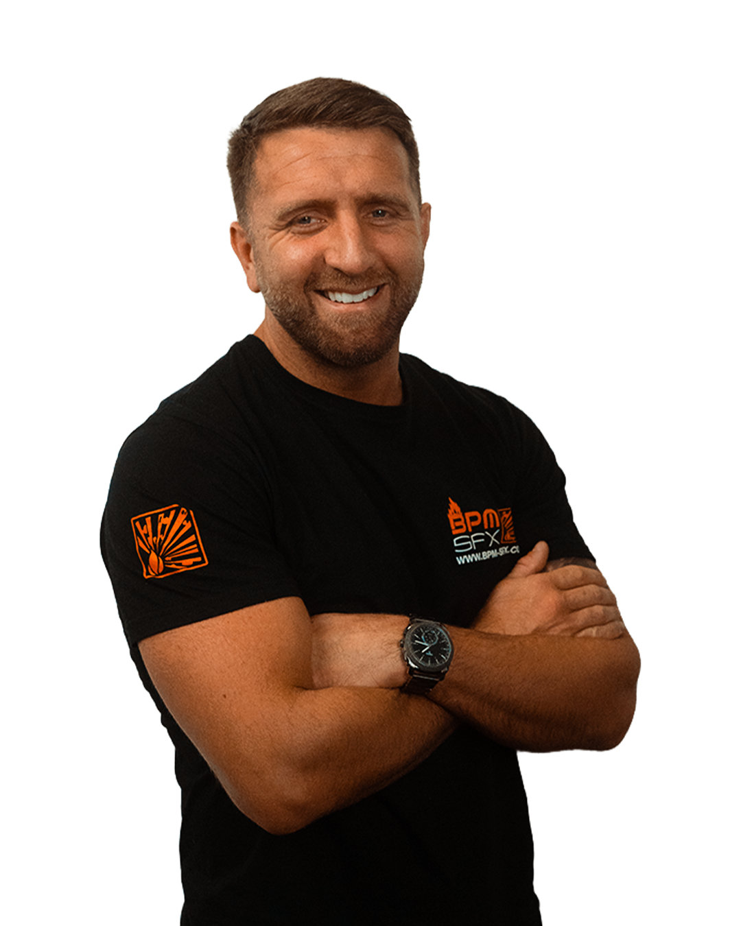 A smiling man with a beard and short hair, wearing a black T-shirt with orange and white logo and text, standing with arms crossed, wearing a wristwatch.